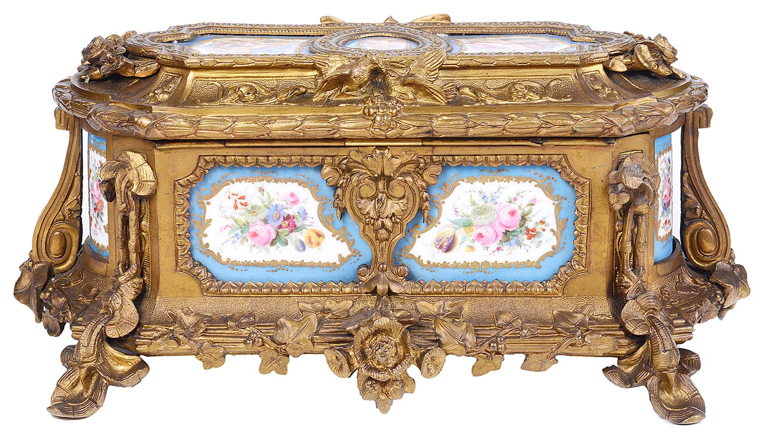 A good quality late 19th century French Sevres style porcelain and gilded ormolu casket, having three inset porcelain panels to the top depicting cherubs in the clouds with musical instruments and flowers, the panels to the sides of exotic birds and