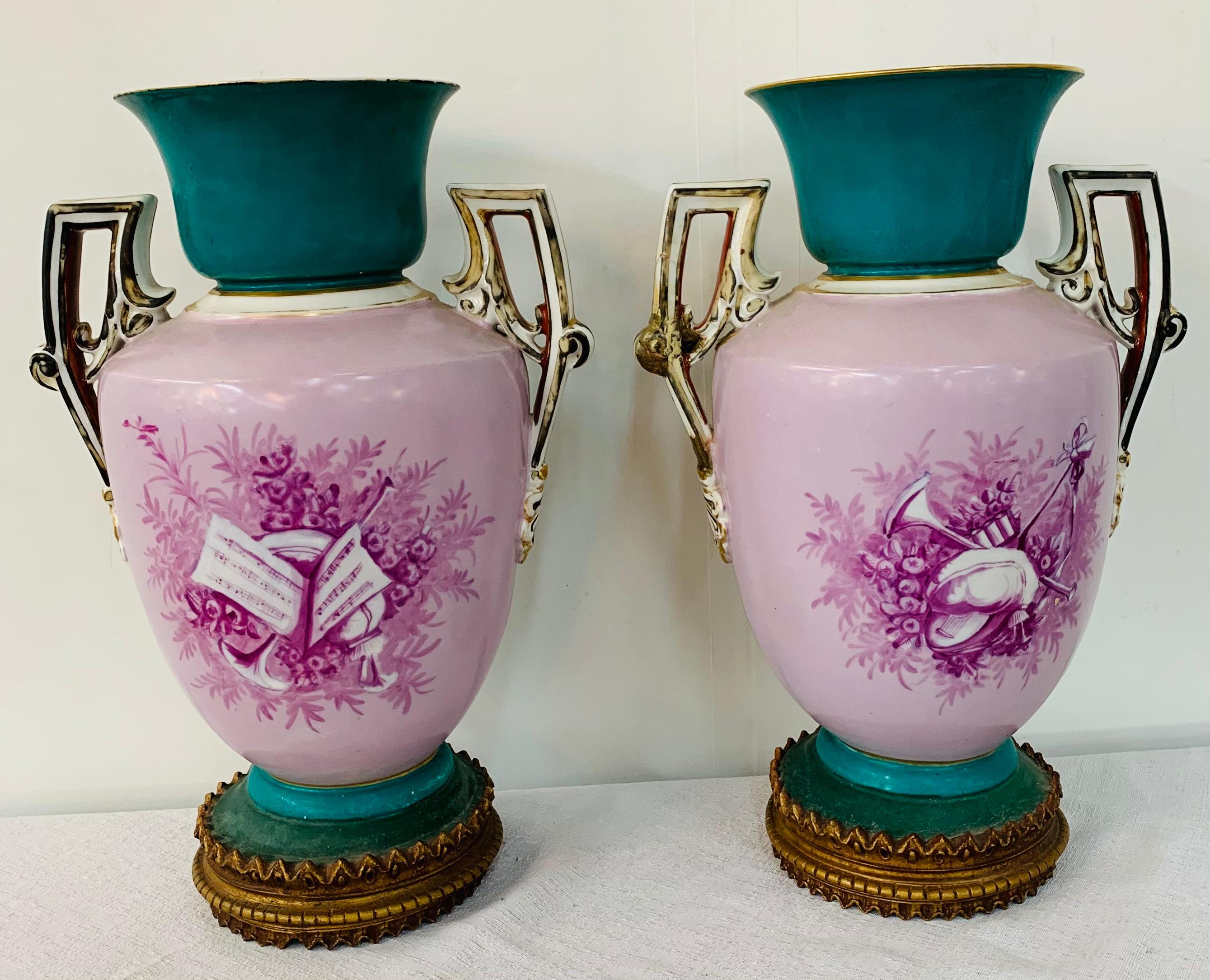 A gorgeous pair of late 20th century French vases or urn in the manner of Sèvres. The vases are beautifully hand painted depicting romantic scene in a fabulous turquoise and purple dominating colors and raised on a gilded bronze round molded