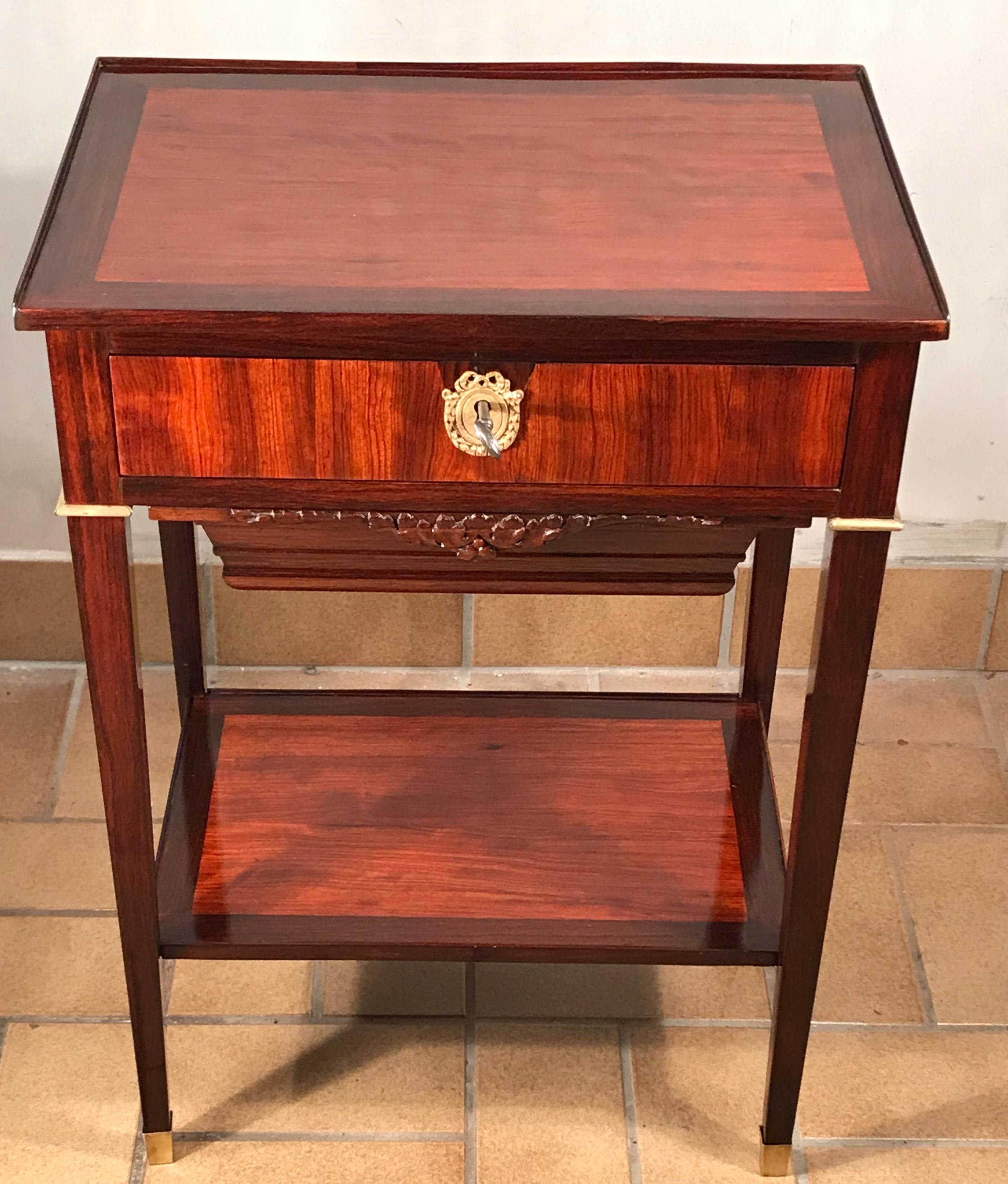 Mesa auxiliar o de costura francesa, estilo Charles X o Restauración 1810-1820.
La mesa está adornada con una hermosa chapa de madera de satén y kingwood. Tiene un cajón central y debajo un cajón para la lana con un frente muy bien decorado.