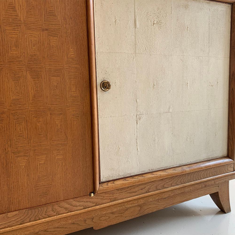 A stunning oak sideboard with diamond patterned parquetry on its central door. Inside is a shelf and two small drawers, and double doors clad with shagreen panels, and two adjustable shelves on each side. 

All the brass hardware and keys are in