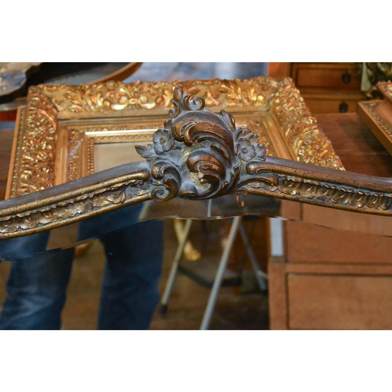 Lovely antique French giltwood shield-shaped wall mirror with bevelled edge. The crest finely carved with leaf scrolls and rosettes. The contoured frame carved in relief with a small flower heads and acanthus leaves,

circa 1920.