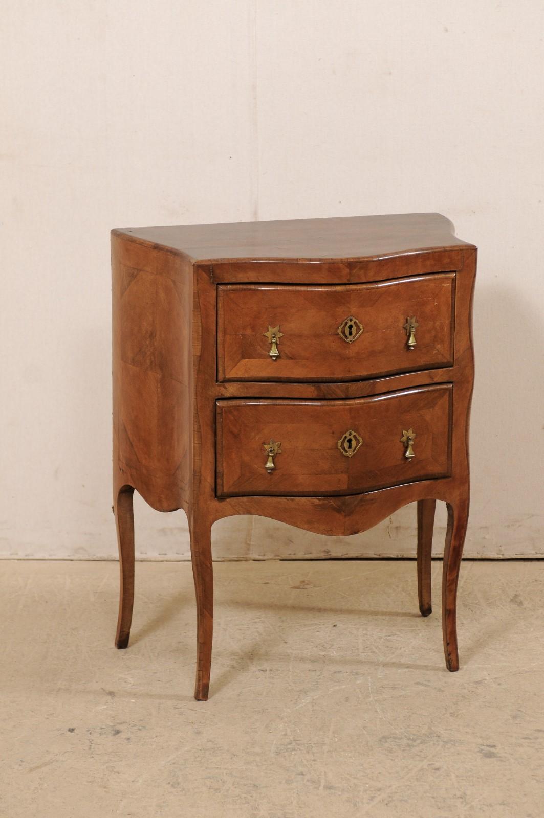 A French raised fruitwood side chest from the turn of the 18th and 19th century. This antique commode from France features a graceful serpentine shaped front and curvy sides, with rear being spread wider than frontside. There is a lovely banding and
