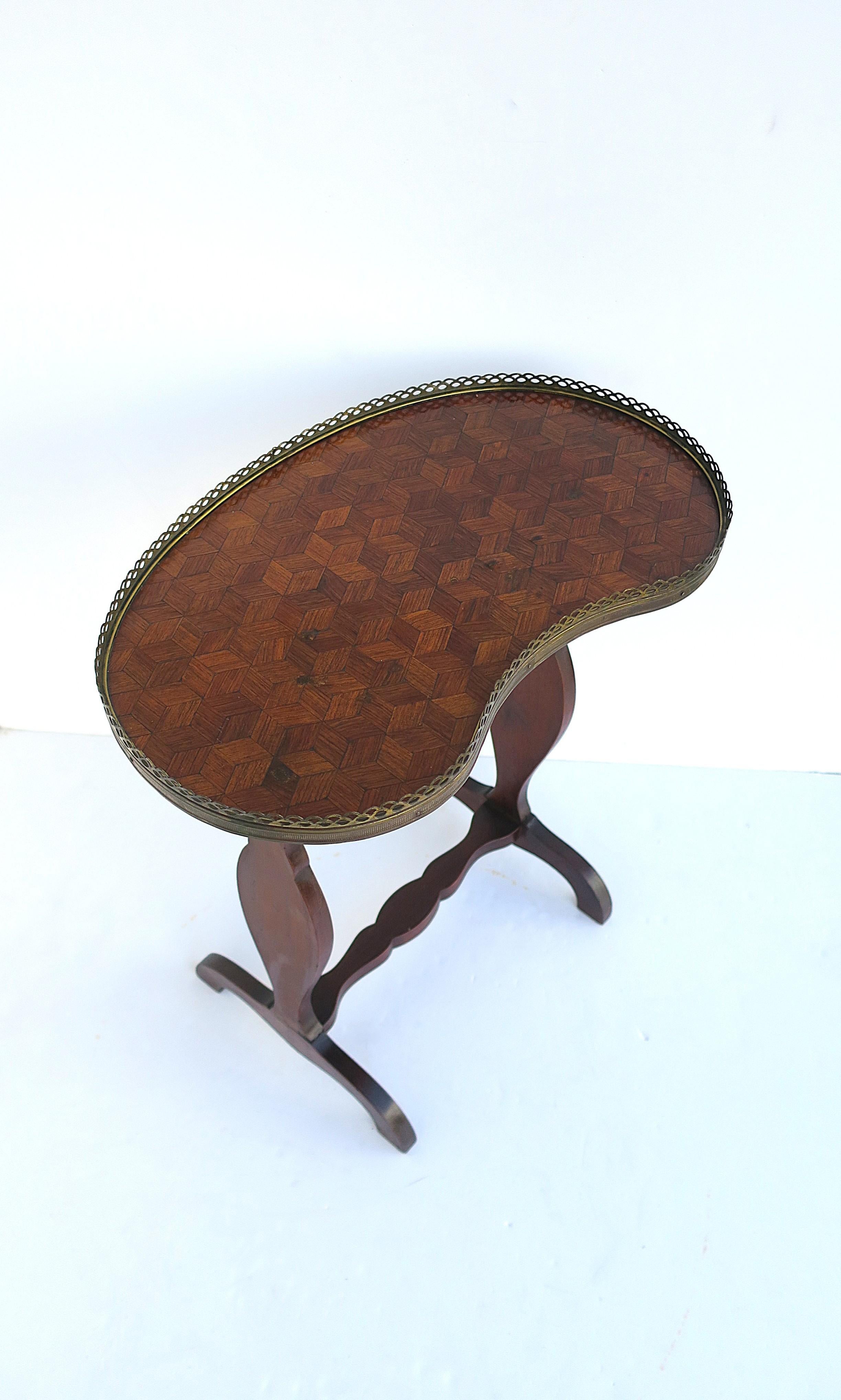 Table d'appoint ou table à boissons ancienne en bois français, avec plateau en marqueterie de cubes et bordure à galerie en laiton, vers le début du 20e siècle, France. La table est d'une riche teinte brune avec un plateau en forme de rein, une