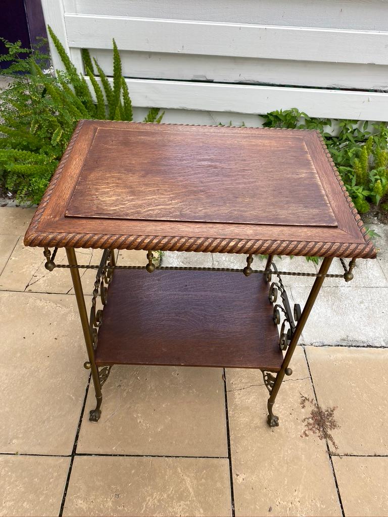 Side table is hand designed and hand made. Hand carved with rope design surrounding the edge of the top. Hand made gallery underneath the top. Wrought iron legs with claw feet. Oak shelf at the bottom. Turn of the century.