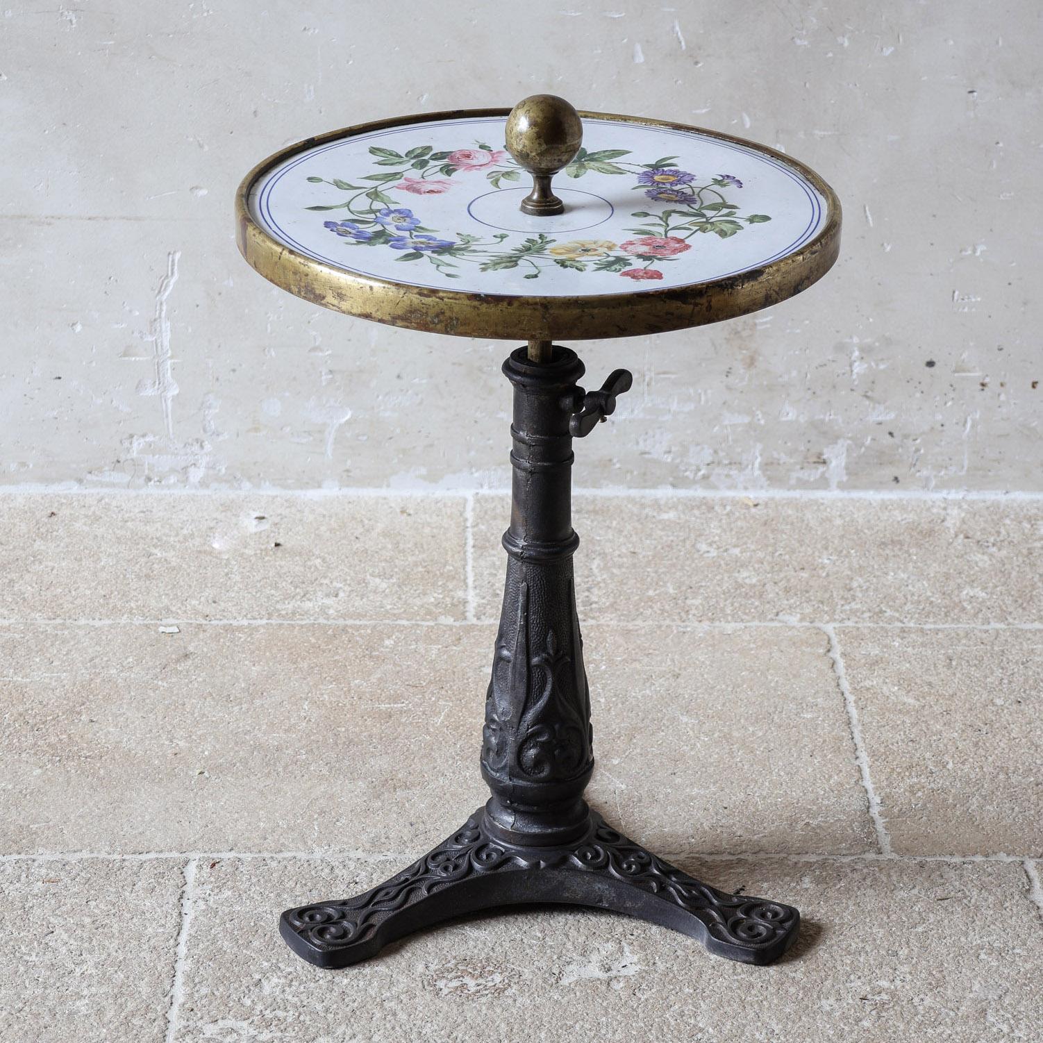 Magnifique table de cocktail ou table d'appoint française unique avec plateau émaillé. Le plateau de table rond en fonte avec une finition en émail de verre, qui est en parfait état, présente des décorations florales vibrantes sur un fond blanc et