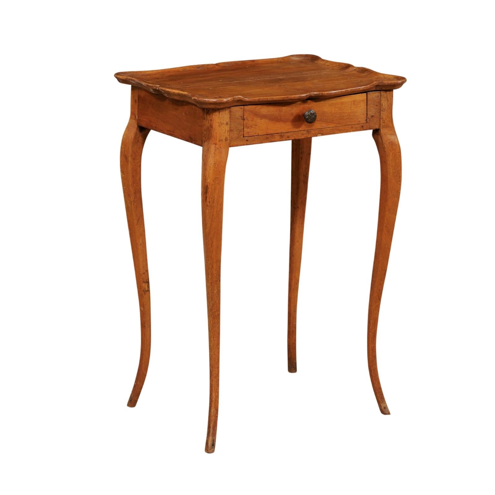 A French side table with single drawer from the early 19th century. This antique table from France features a rectangular-shaped top with sweet scalloped pie-crust edge. The slightly overhanging top rests above a simple apron which houses a single