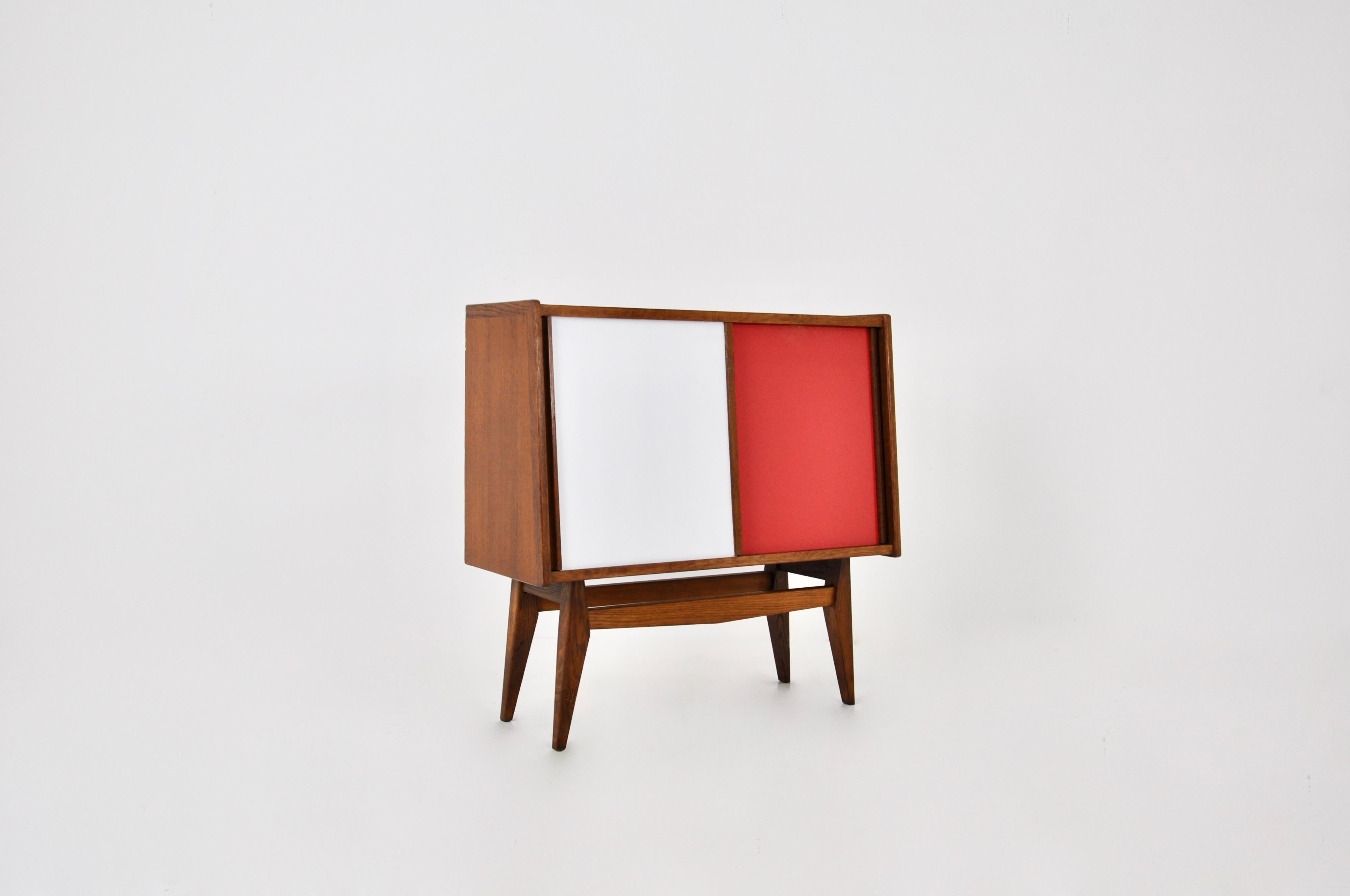 Wooden sideboard with two sliding doors in white and red. Wear due to time and age of the sideboard.