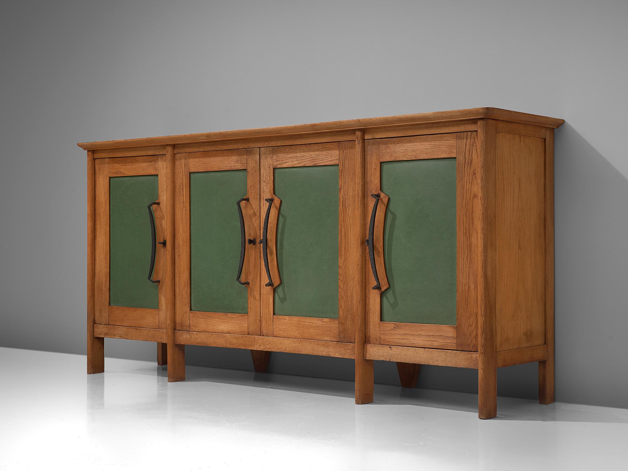 Large sideboard in oak and iron, France, 1940s.

This large oak sideboard with green leatherette inlayed doors. The high sideboard has modest and rustic look. The four doors are finished with a leatherette panel en large, curved handles made in