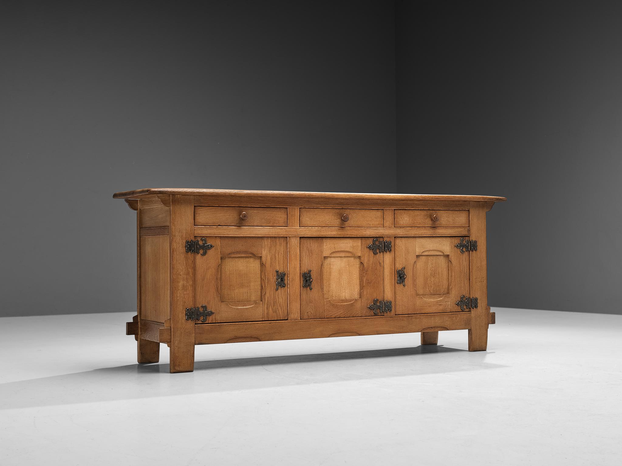 Sideboard, oak, metal, France, 1960s. 

This sturdy yet elegant sideboard is executed in warm stained oak and manufactured in France. Not only features this piece remarkable visual qualities, it also offers great storage space. Three doors are