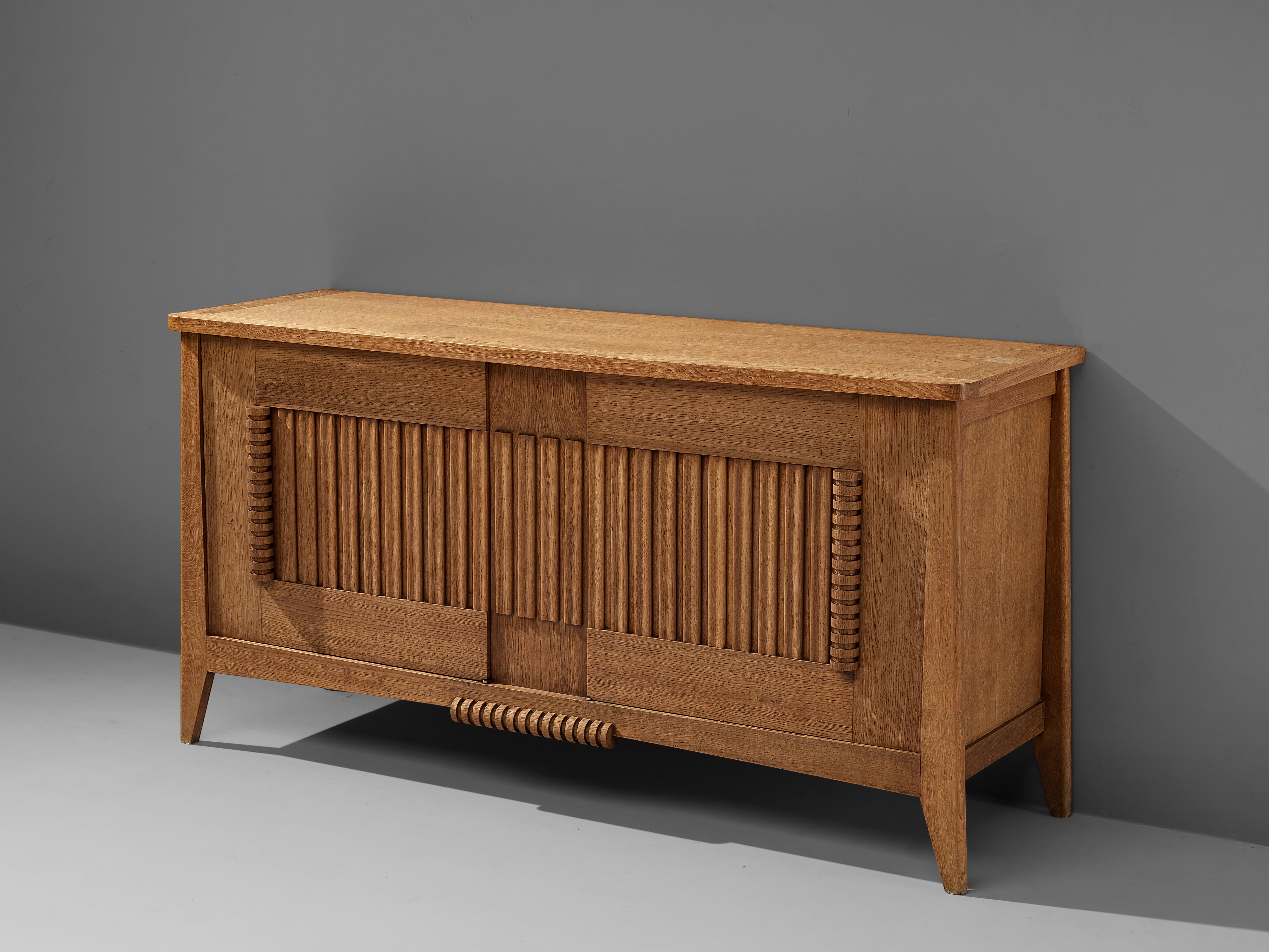 Sideboard, oak, France, 1950s

Beautifully decorated sideboard in a late art deco style. The sideboard is gorgeously ornamented on the doors with vivid carvings. The two embellished doors open towards each other, and the grooved elements can be