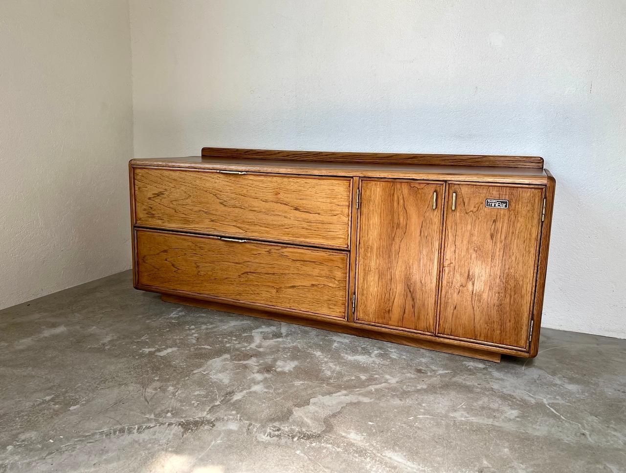 This rare English sideboard, stamped Stanley Furnitures, is the result of a partnership with Electrolux at the time to offer an elegant living room sideboard that can accommodate a small refrigerator. The size of this space is, with the two vertical