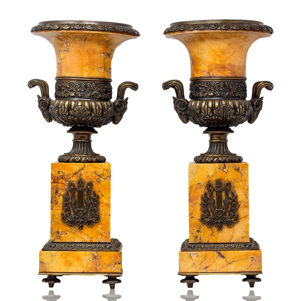 Angewandte Leierdekoration

Das Paar steht auf vier gegossenen Bronzefüßen mit einem Sockel aus Siena-Marmor mit einer aufgesetzten Bronze-Rollwerksbordüre. Die zentrale quadratische Säule mit einer bronzenen Schwanenhals-Lyra-Harfe, die von