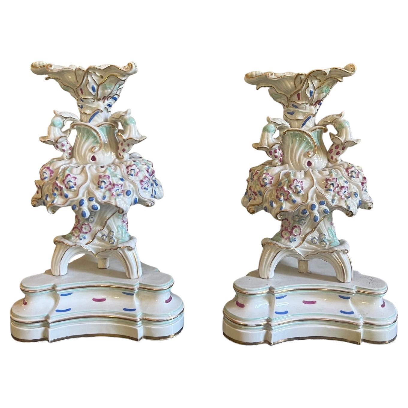 Pair of hand painted Jacob Petit porcelain tripod epergnes on triangular bases. Made in France around 1850. Hand painted floral motif with gilt, mauve green and blue paint detailing. They are signed JP inside each base as well as hand