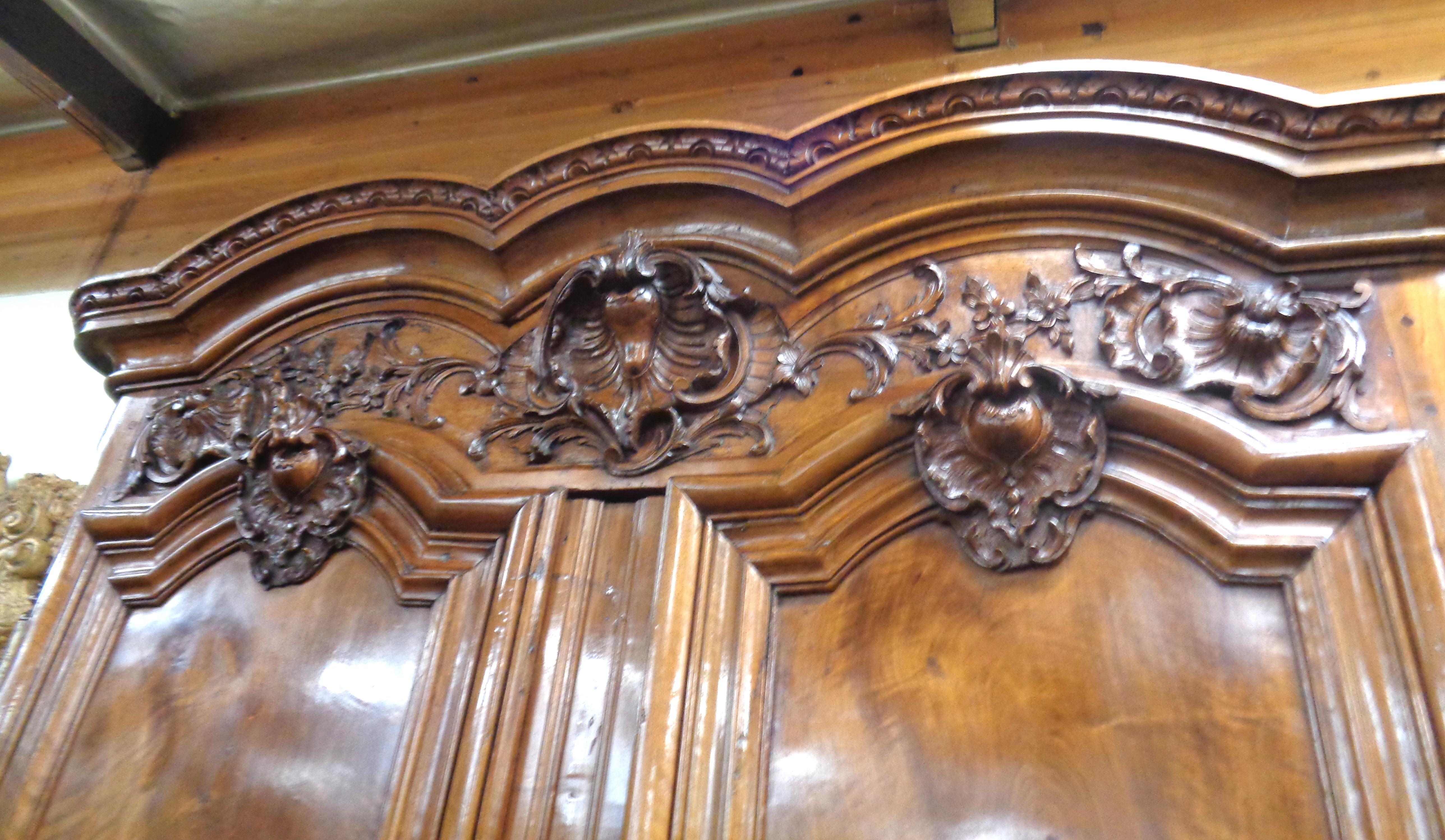 French Chateau carved walnut Lyonnaise armoire with a highly stylized cornice at the top. There is magnificent three dimensional carving below the cornice and a deeply carved coquille in the center. The doors are made of matched walnut and have