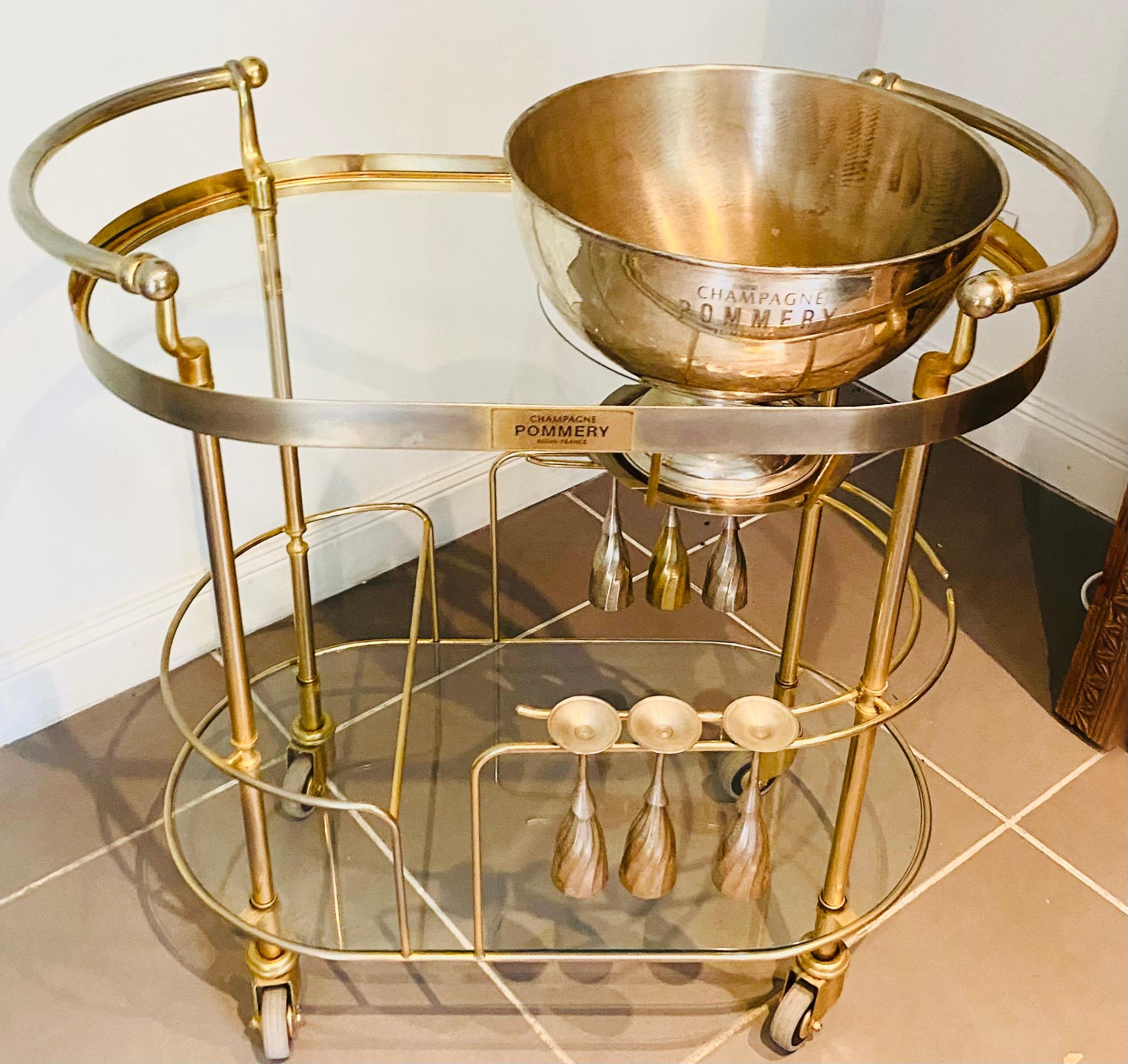 Beautiful and rare Art Deco champagne trolley or bar cart with a curved two-tier frame in chromed brass and glass - Pommery
The upper level has a bowl, champagne bucket, ice bucket, wine cooler for ice in Silver Metal.
The second level has its six