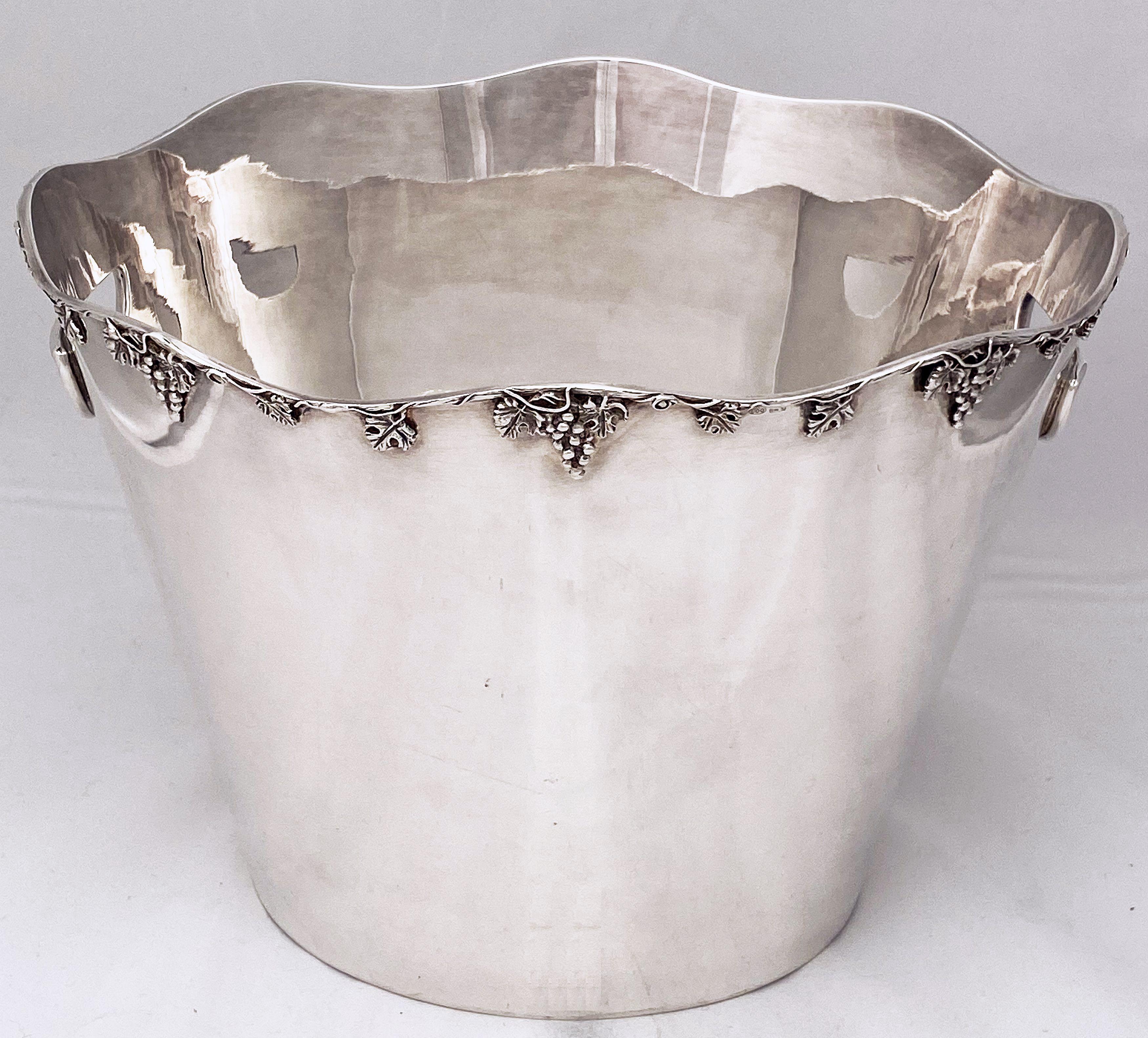 A fine French champagne bucket or wine cooler featuring a gracefully undulating top edge with relief of grapes and grape leaves, and inset opposing handles.

Impressed hallmark for .800 silver.