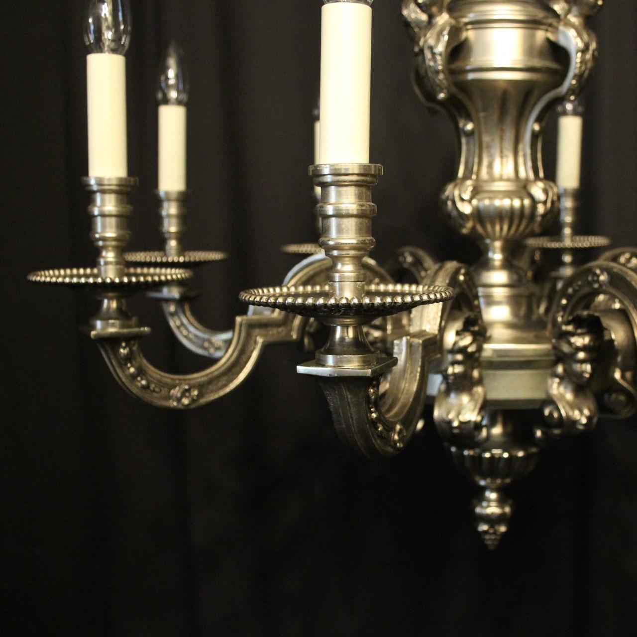 A French silver gilded cast bronze 8-light antique chandelier in the manner of Andre Charles Boulle, the square gauge scrolling arms with ornate bobéches drip pans and candle sconces, issuing from a pierced central urn stem with four female