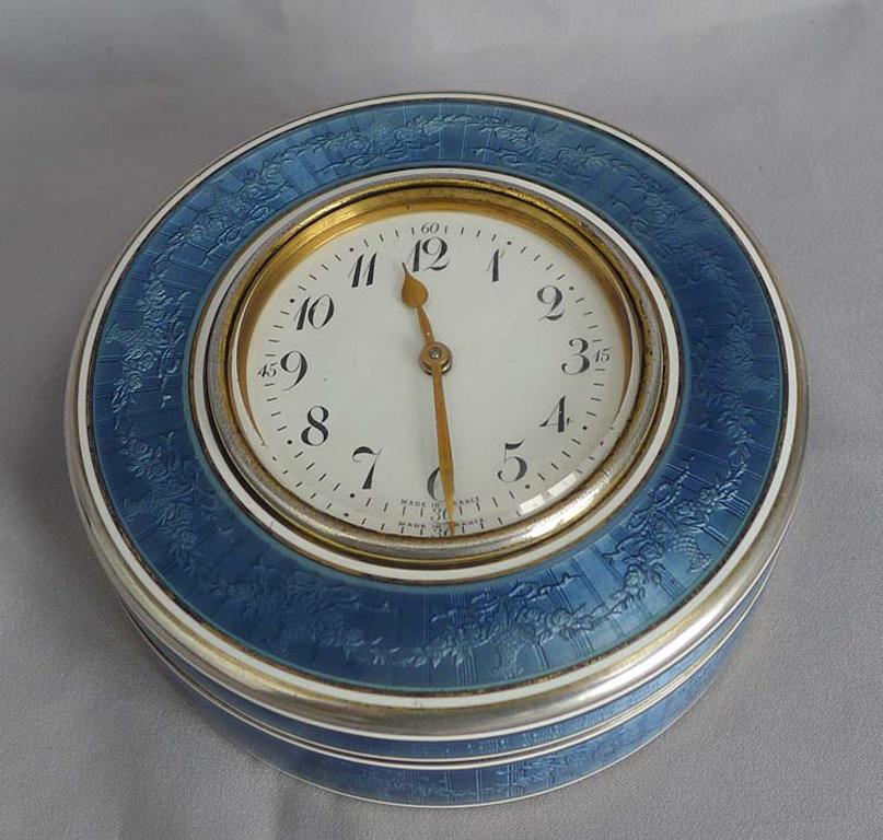 A most unusual and quite beautiful, large silver gilt and florally decorated French grey/blue guilloche enamel box clock. The circular box with engine turned silver gilt base with bands of silver and white enamel with a wide floral guilloche enamel