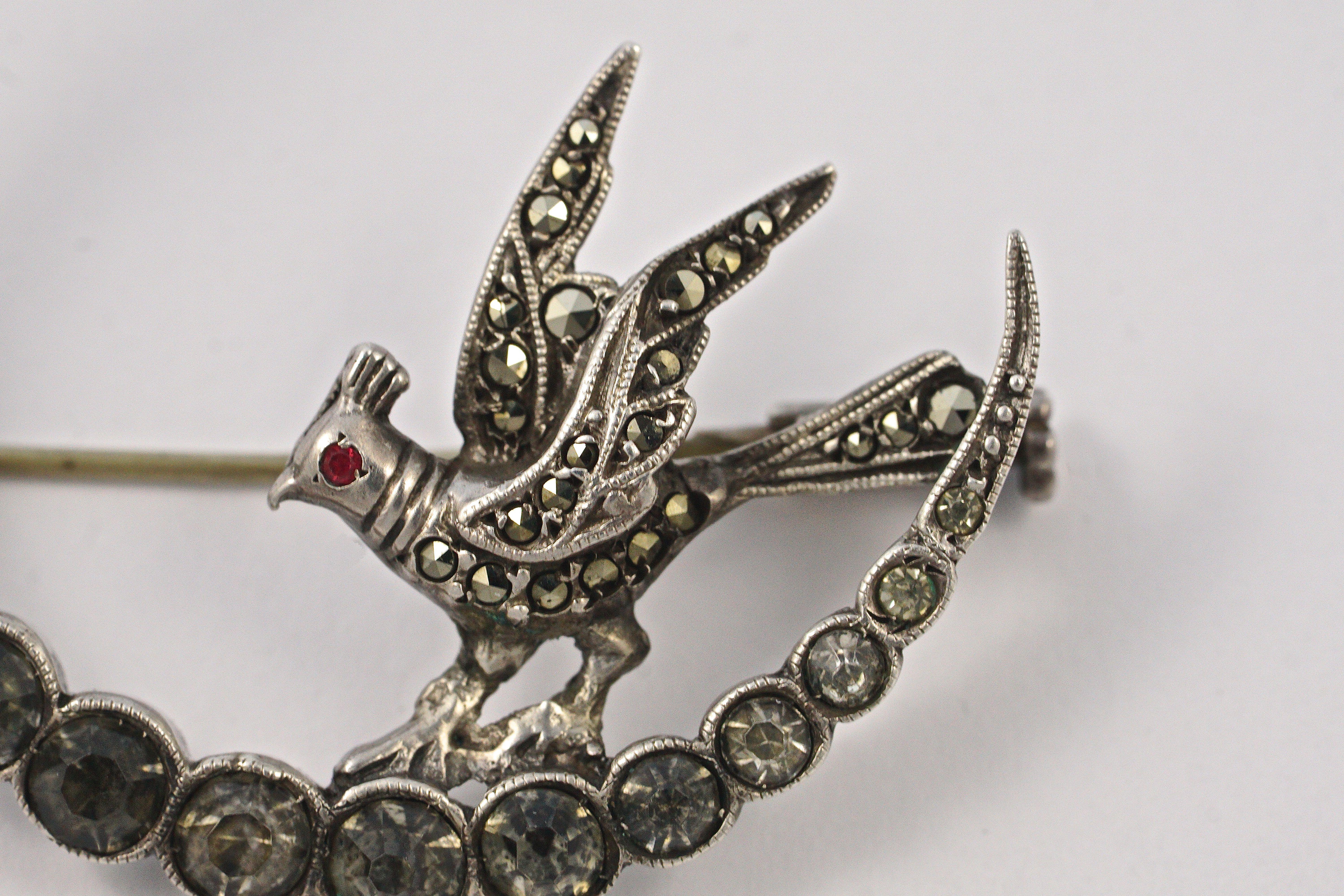 
Delightful French silver crescent moon brooch set with rhinestones, and featuring a marcasite bird with a red crystal eye. Measuring diameter 3.7cm / 1.45 inches. The brooch tests for silver and is marked Depose, which is a European term that means