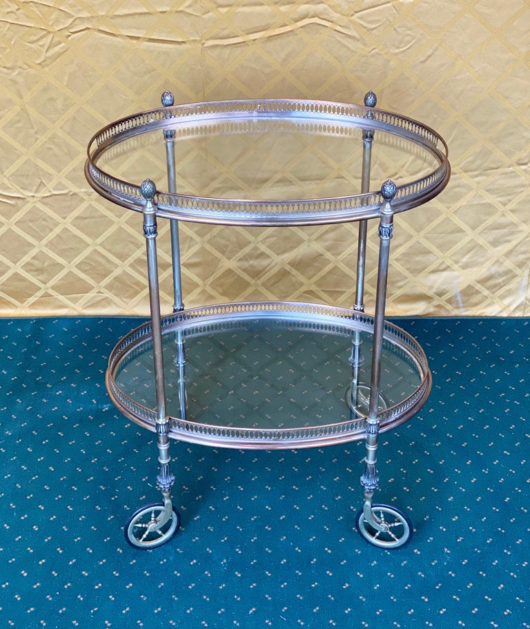 Elegant round silver metal French bar cart attributed to Maison Baguès, circa 1950. Polished silver metal throughout, having two tiers with glass trays (the upper one is removable), and four free-rolling rubber wheels. The top tray separates to