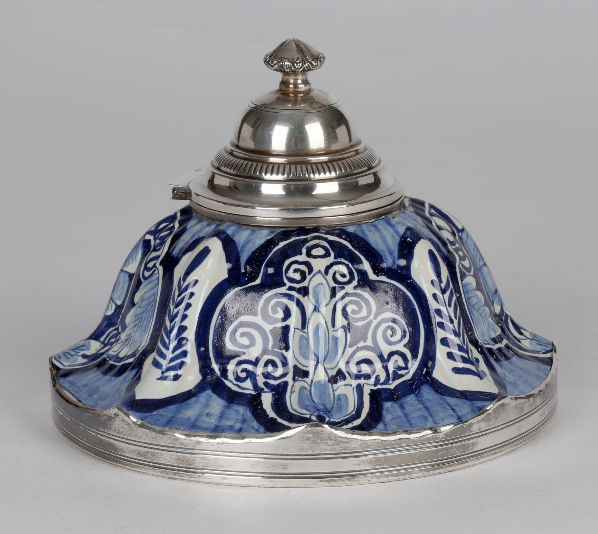 Ein ungewöhnliches, in Silber gefasstes französisches Fayence-Tintenfass aus dem 19. Jahrhundert, handbemalt mit blauen und weißen Motiven. Das gewölbte Tintenfass steht auf einem abgerundeten Sockel mit hochwertigem Silberrand. Der geformte und