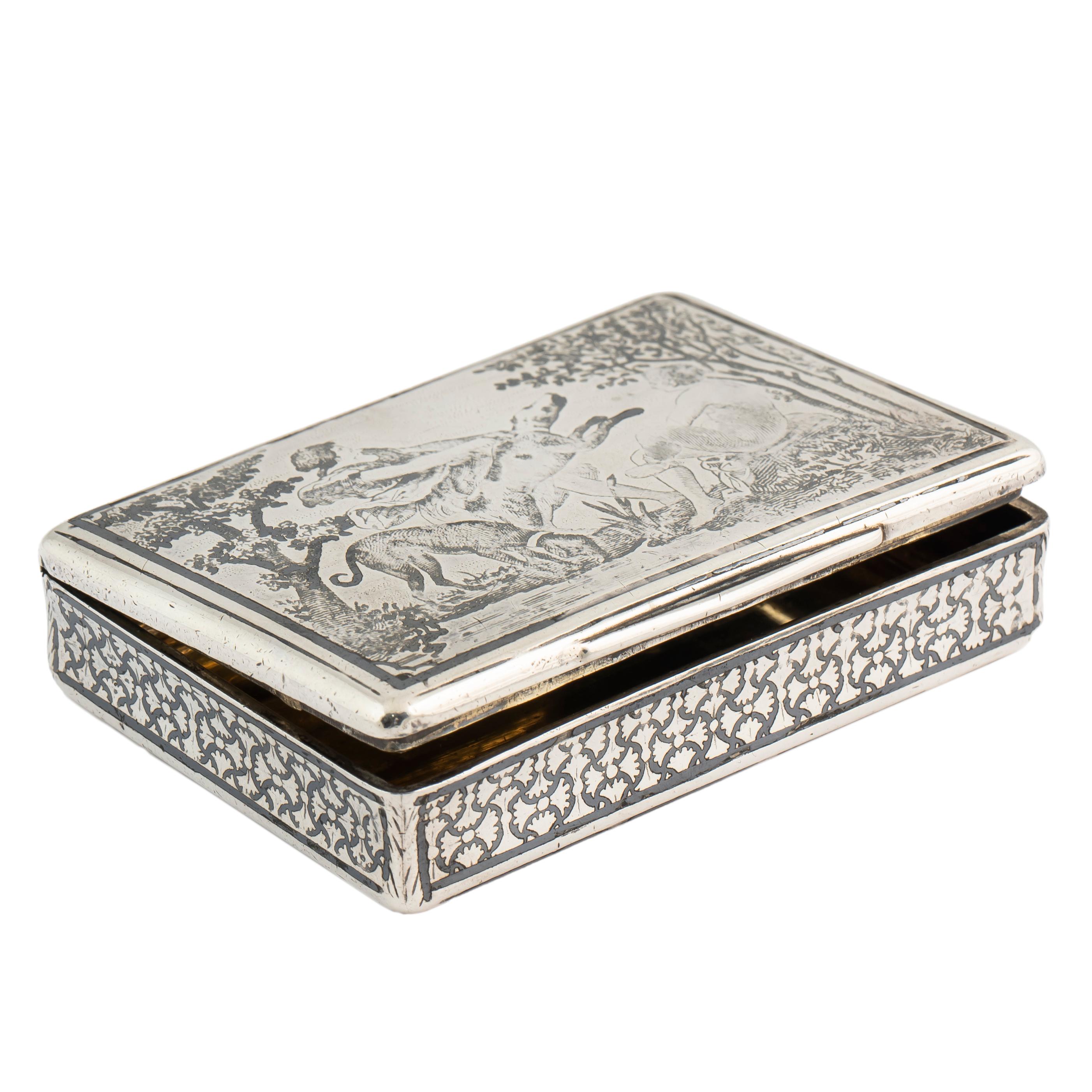 A rare French silver nielloed snuff box featuring a mythological hunting scene on the cover within a finely detailed wooded landscape, a hound barking up a tree is being restrained by a young warrior while a seated nude observes on the right. The