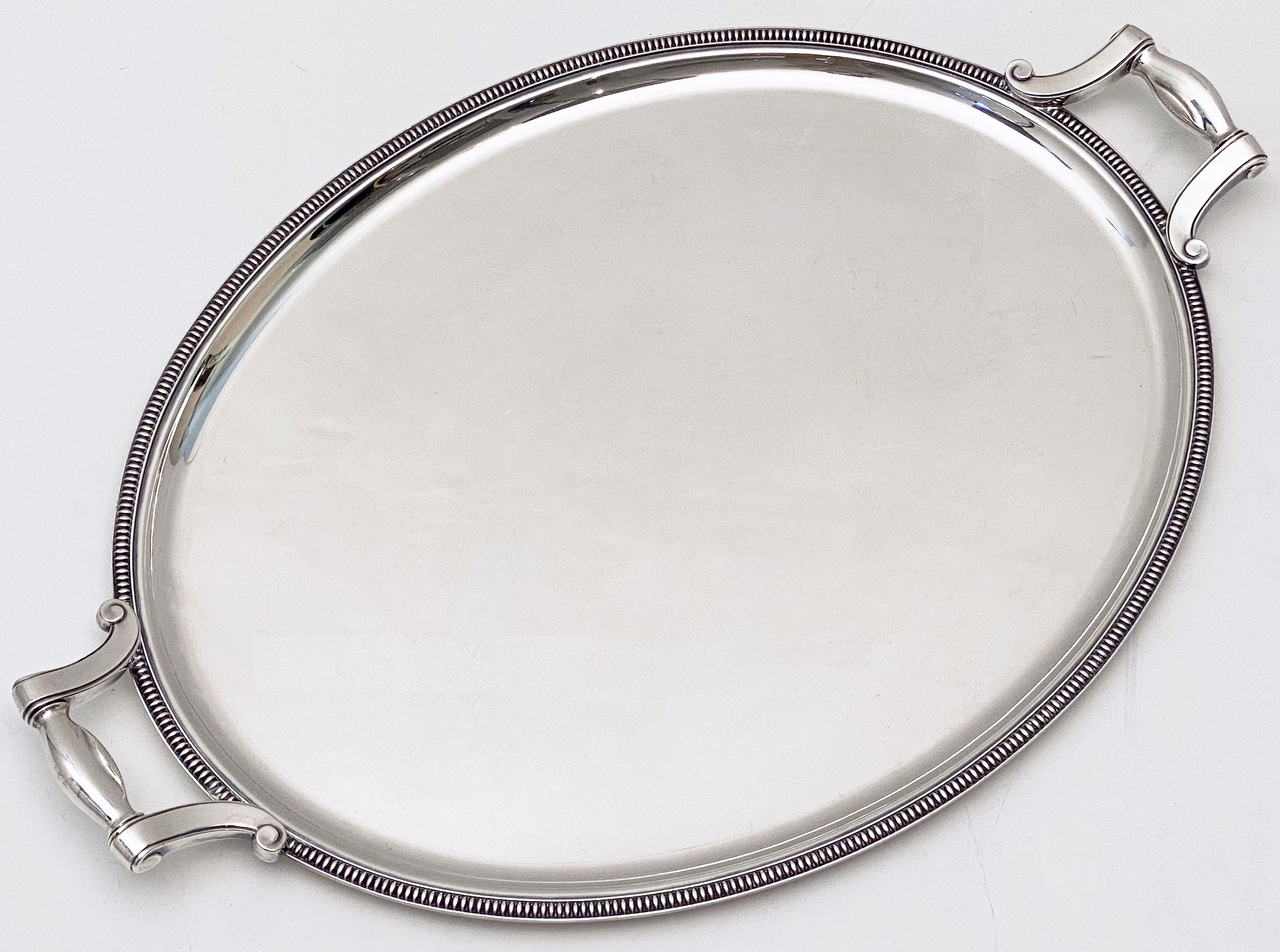 A handsome French oval serving or drinks tray of fine plate silver, by the celebrated silversmiths, Christofle, featuring two opposing handles and a stylish raised edge around the circumference.

Marked on handle: Gallia - Christofle - France.