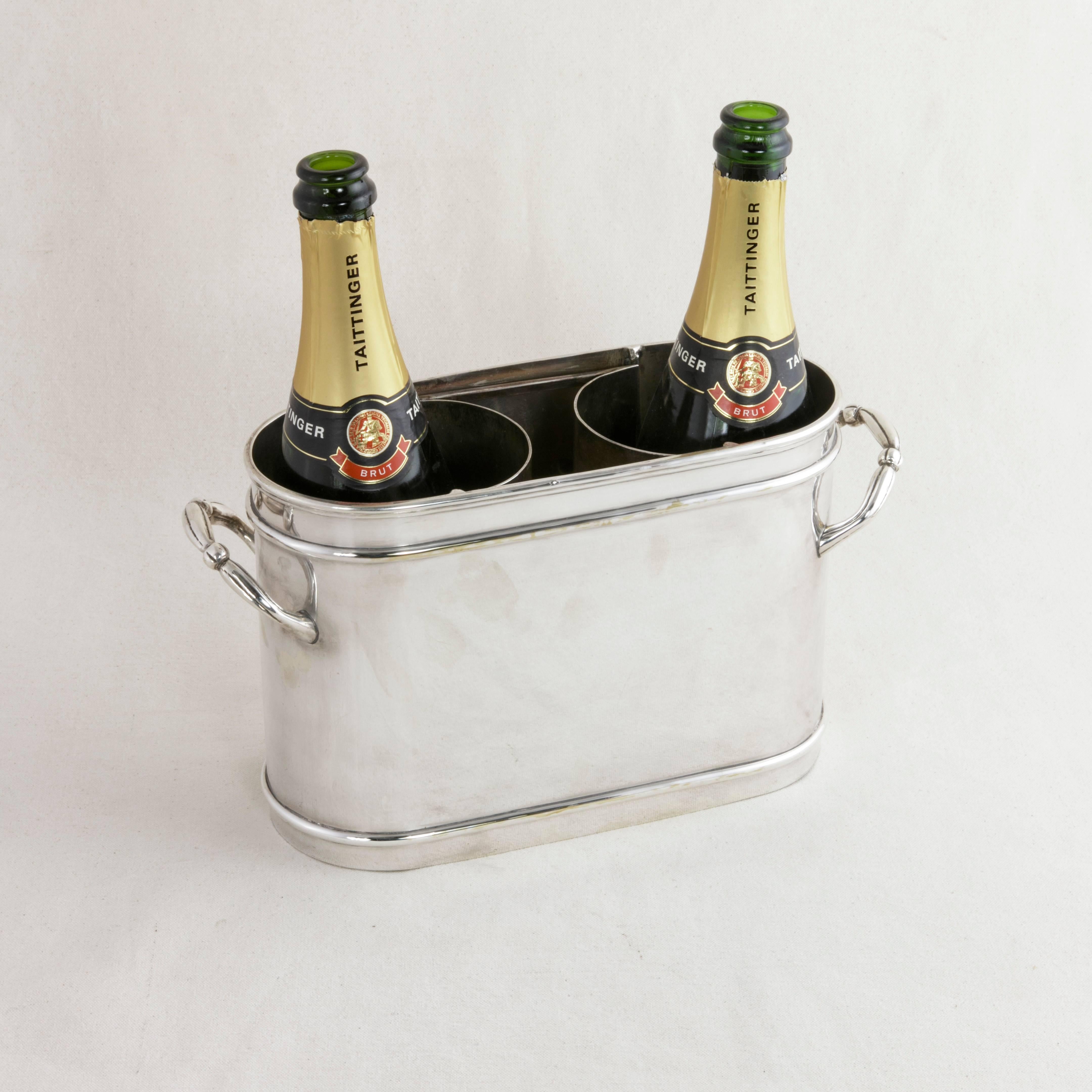 This unique French silver plate champagne bucket or wine chiller from the mid-20th century has an unusual oval form detailed with banding and features a removable pierced divider that separates the two bottles it accommodates. Two handles allow for