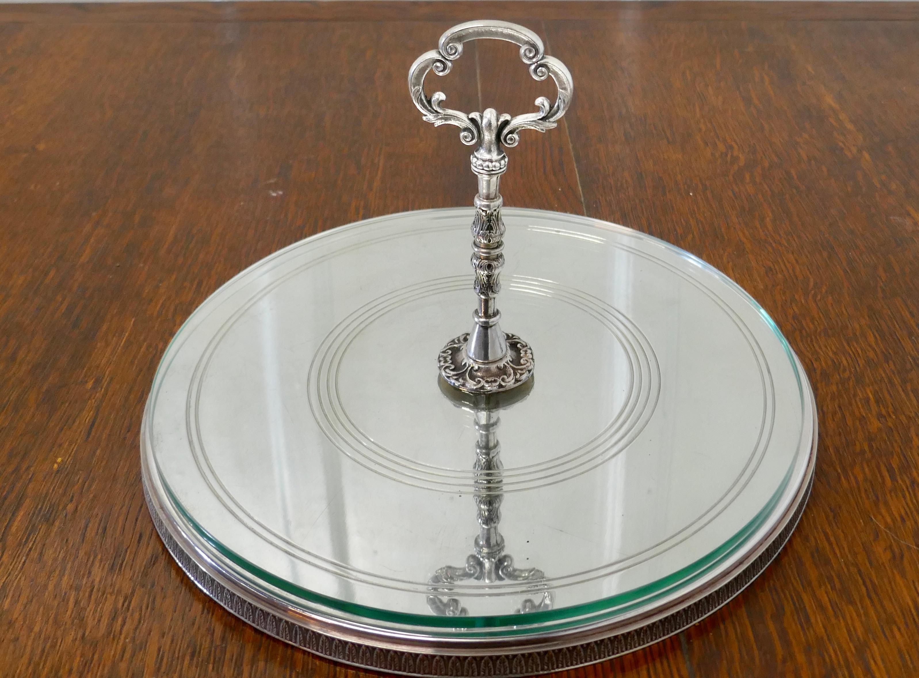 French silver plated and glass cake stand

A pretty sliver plated stand with a central handle, the stand has a glass cover which sits on the decorative base giving the illusion of the bottom being in mirror 
The stand is in good used condition it