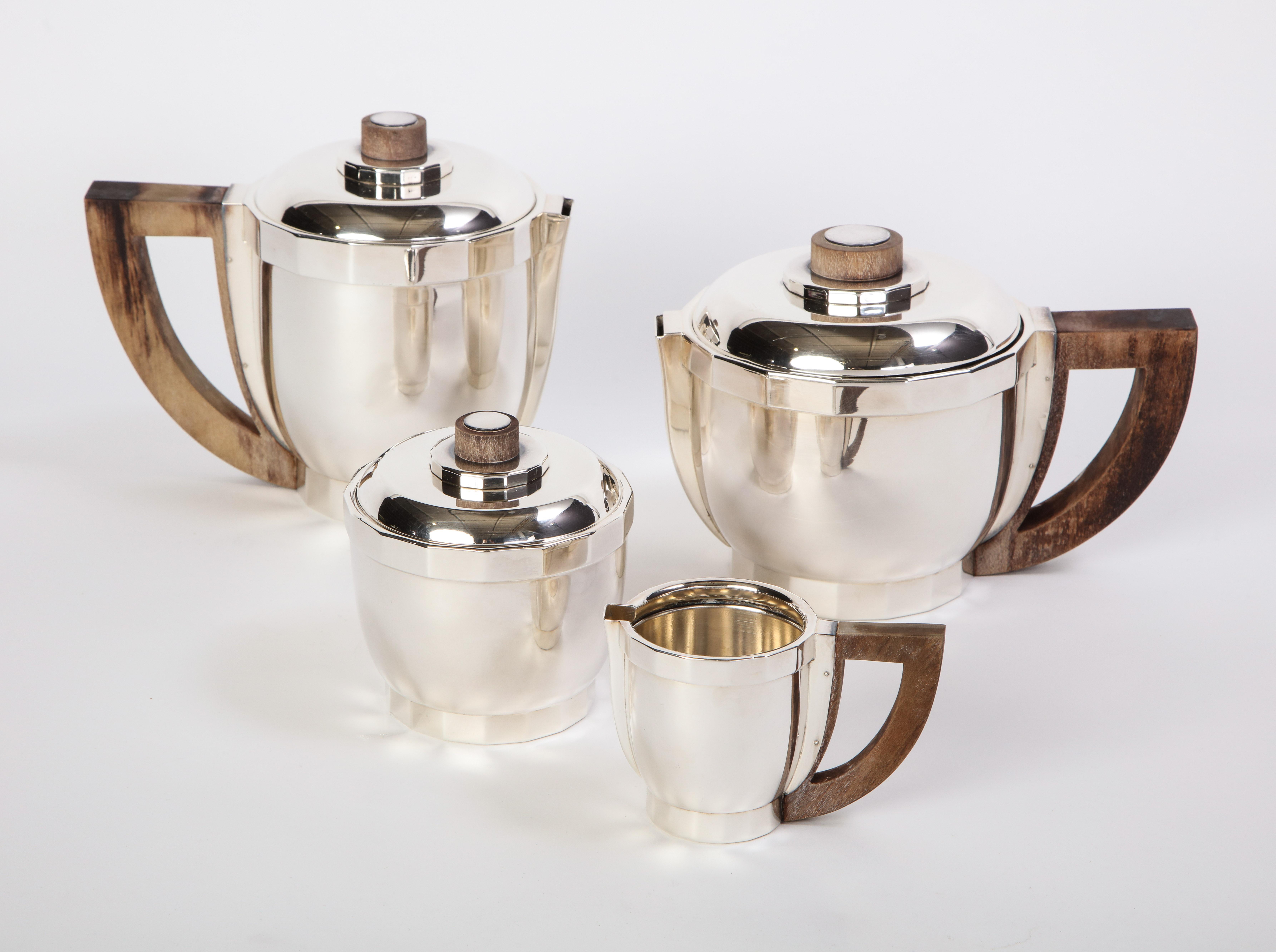 A French silver-plated Puiforcat four-piece tea and coffee service with wooden handles. Comprising a teapot, a coffee pot, a creamer, and a covered sugar bowl. All pieces are marked underfoot for Puiforcat France, circa 1990. The polished silver