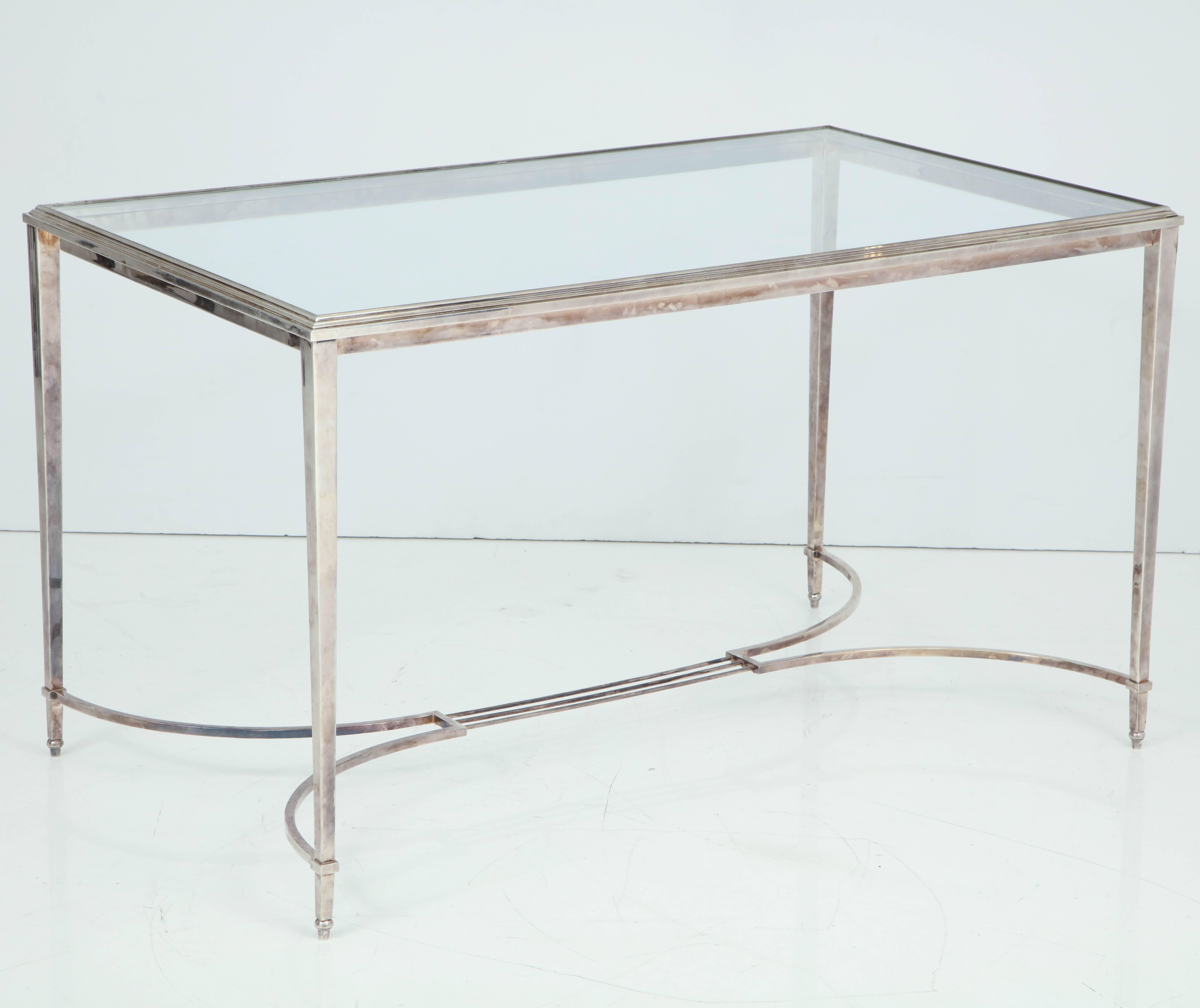 French silvered bronze vanity or writing desk with glass top, tapering square legs, and delicate stretcher base, circa 1940.