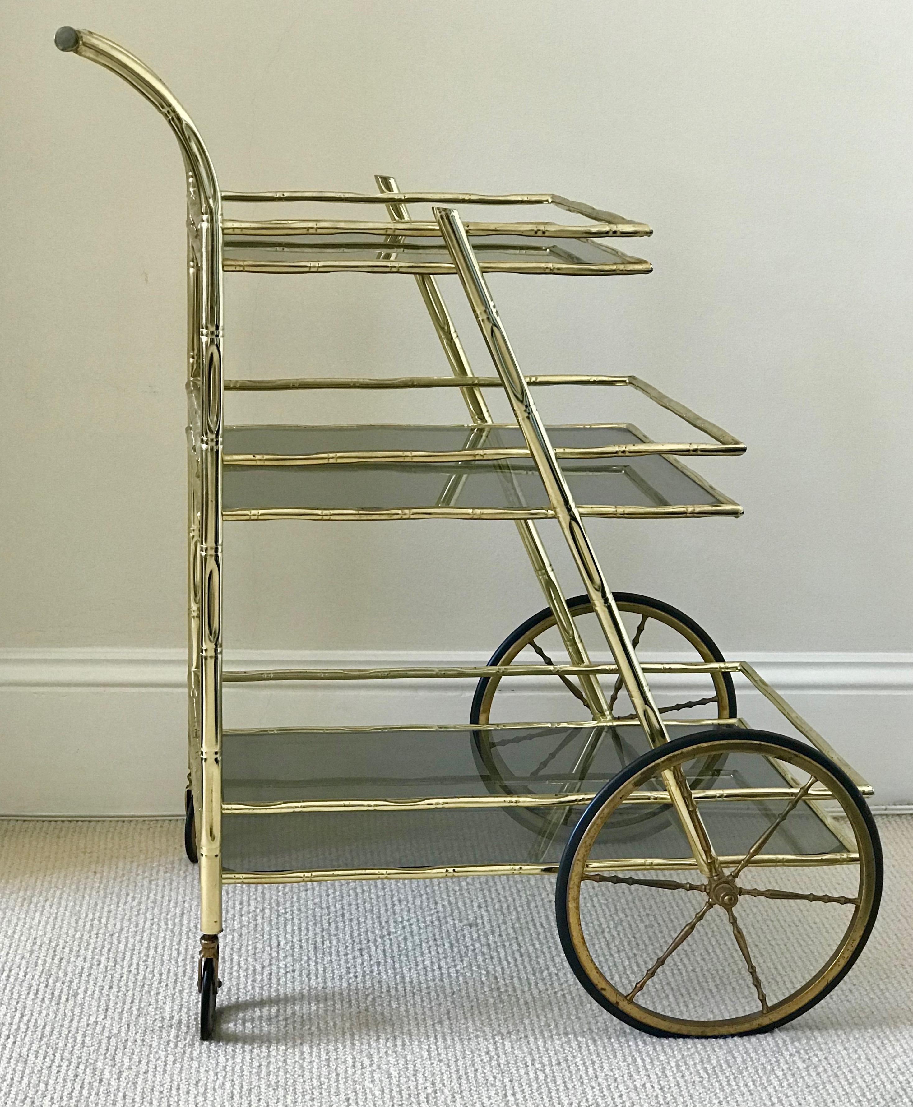 French serving / bar trolley features a simulated bamboo brass frame and three graduated tiers with smoked glass shelves.
Previously purchased from Christies London.
 