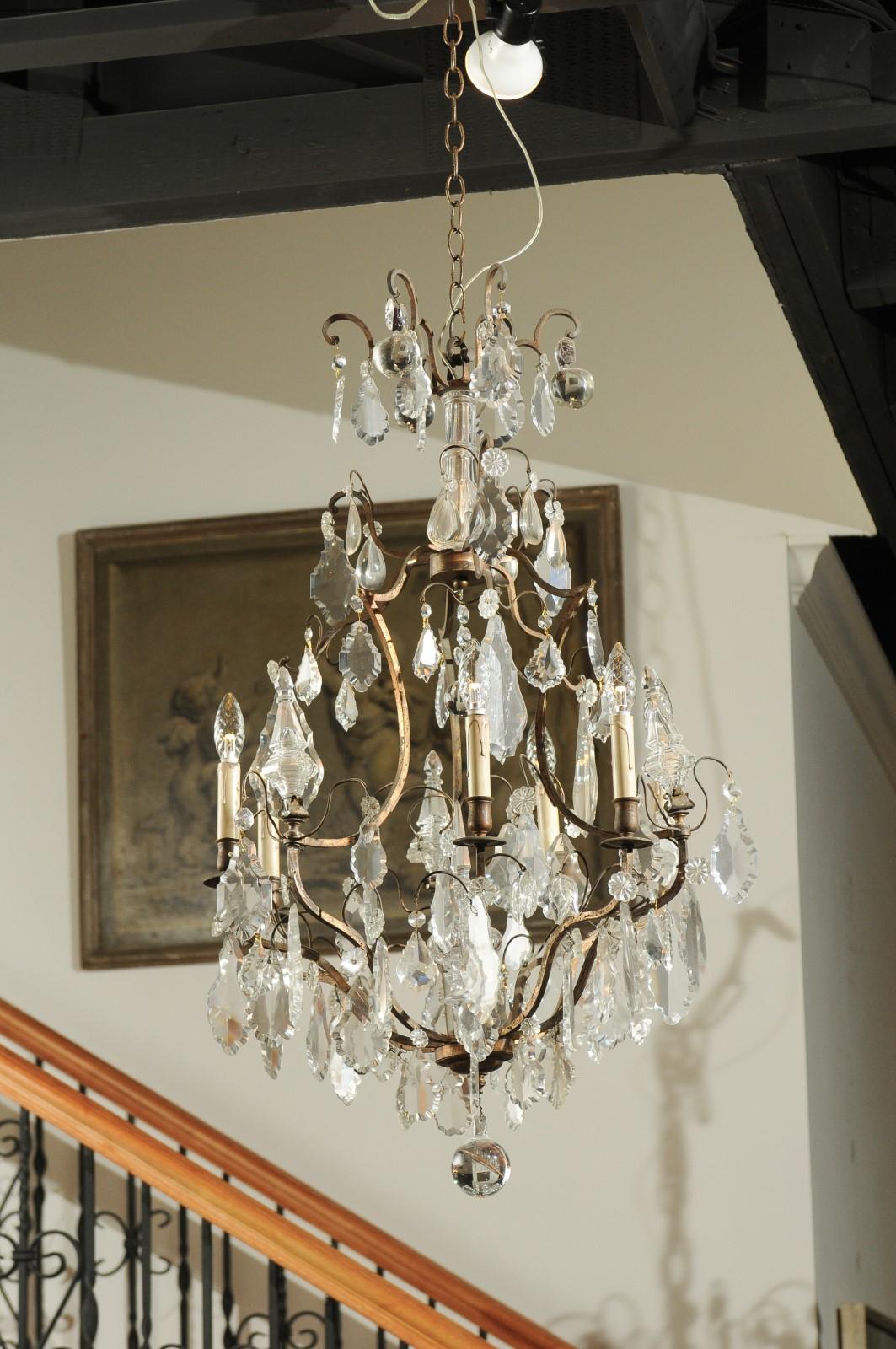 A French six-light crystal chandelier from the late 19th century, with iron armature and obelisks. Born in France during the Belle-Époque era, this exquisite six-light chandelier features a scrolling iron armature accented with pendeloques, rosettes