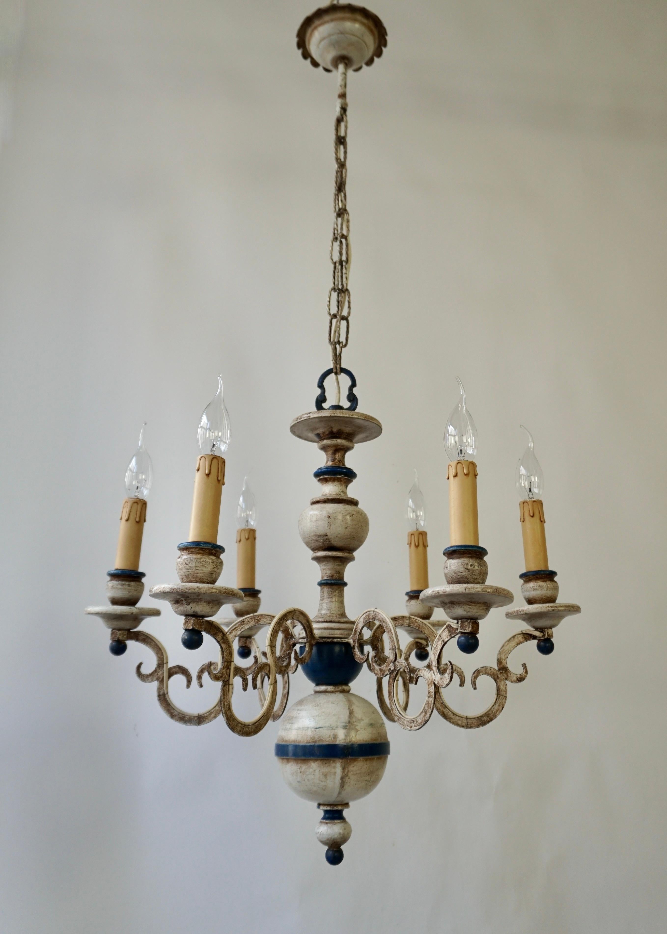 A French six-light painted wood and metal chandelier. 
This mid-20th century French chandelier features a carved wood column with fluid s-shaped swooping arms lifting up and out from its centre. This column features a serious of bulbous shapes.The