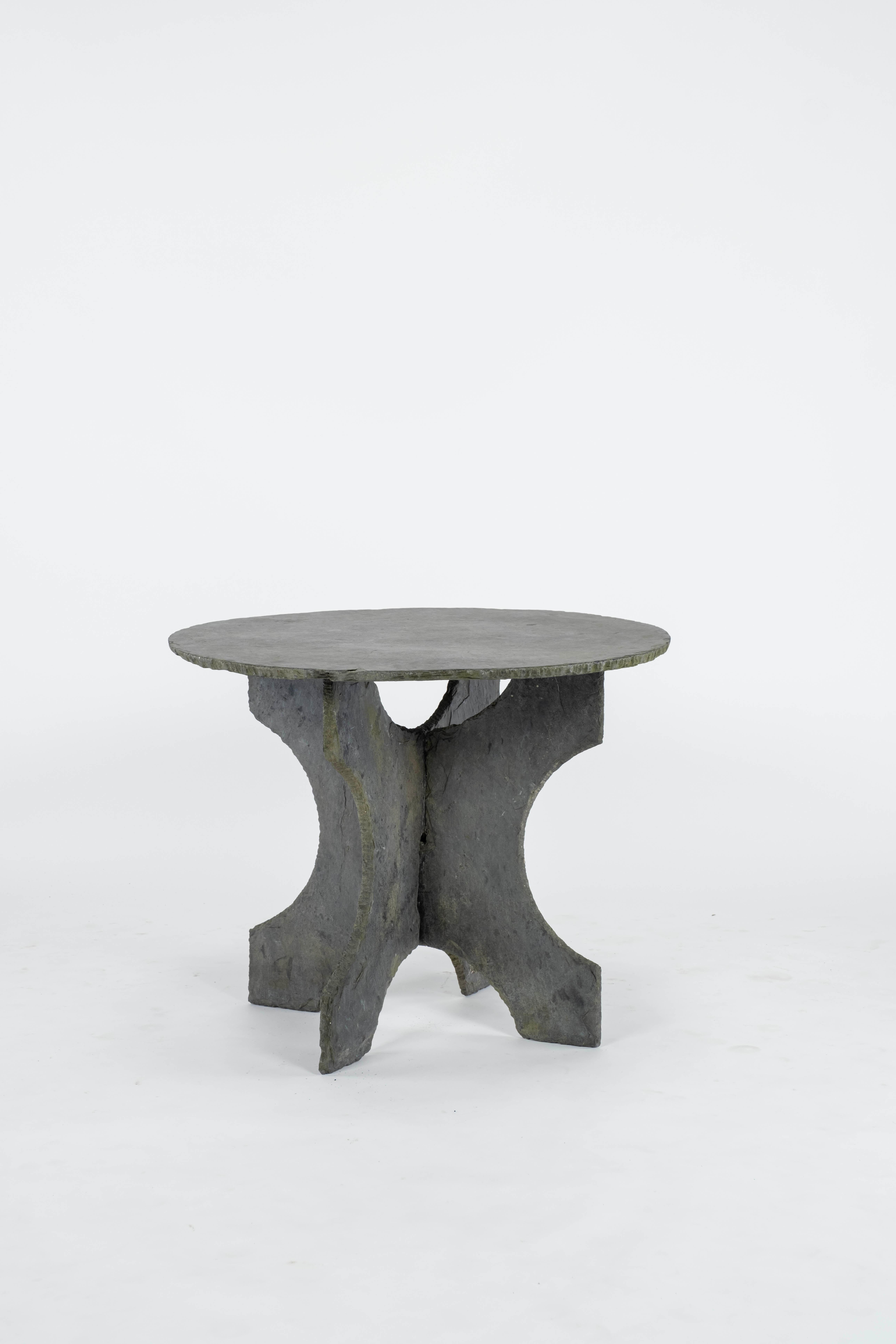 A vintage round slate table with a base that is made up of two interlocking pieces. These pieces come from the Ardennes area of France.