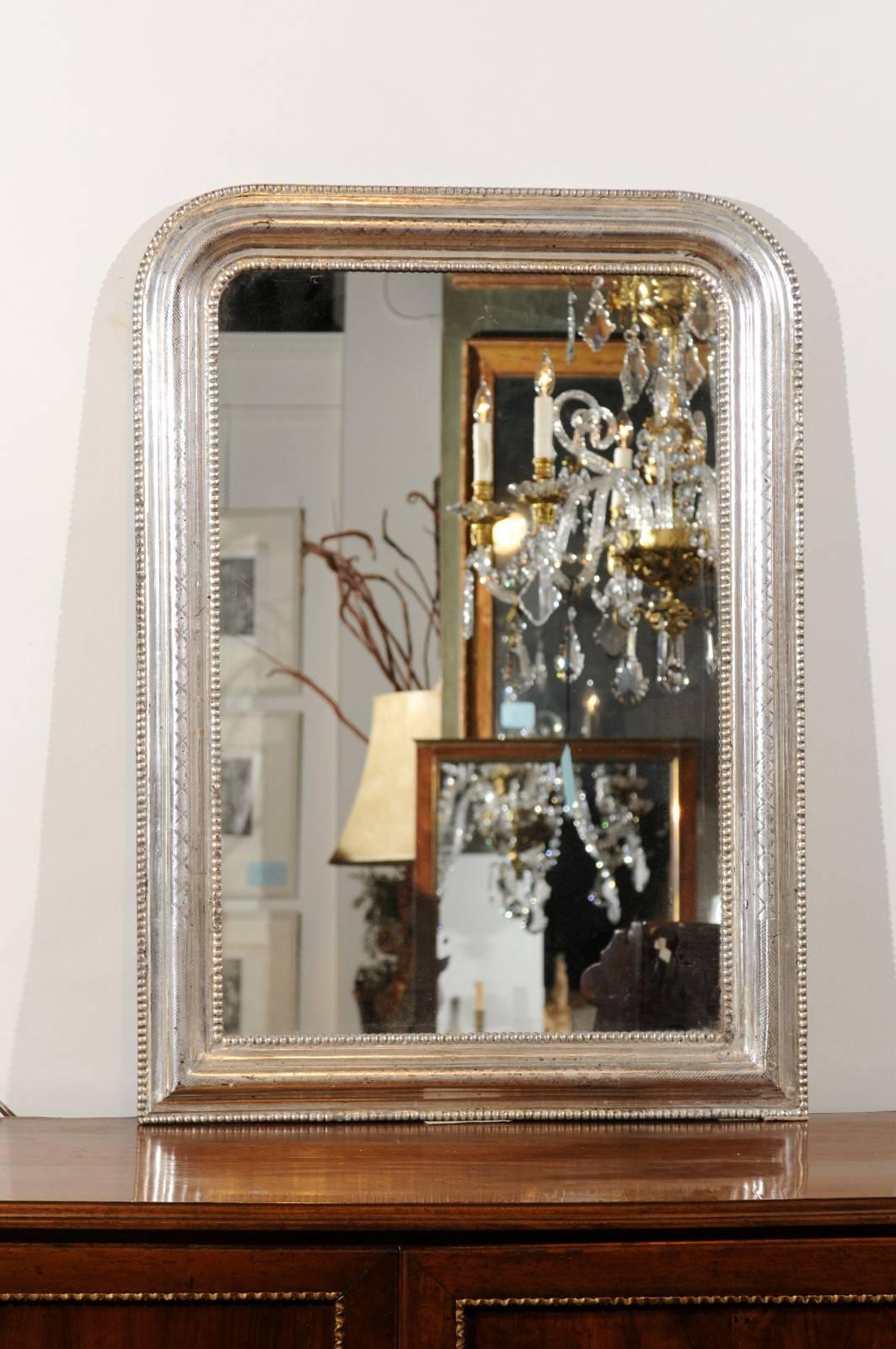 A French small size silver gilt Louis-Philippe mirror with beaded motifs from the late 19th century. This French Louis-Philippe style mirror was born in the later years of the 19th century, at a time when France was revisiting the various styles of