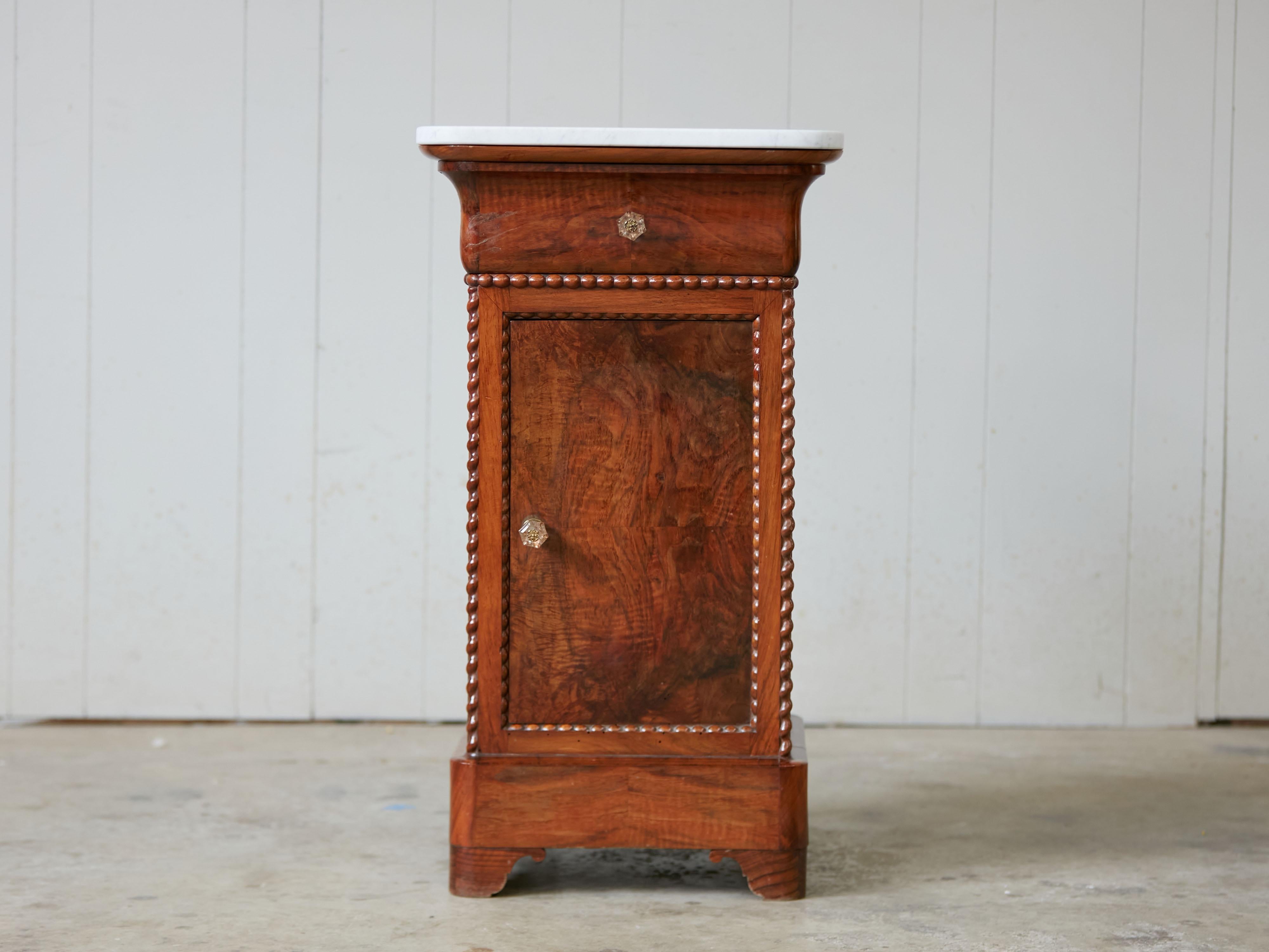 A French walnut small cabinet from the early 20th century, with white marble top and twisted motifs. Created in France at the Turn of the Century, this walnut cabinet features a square white marble top sitting above a single drawer over a single