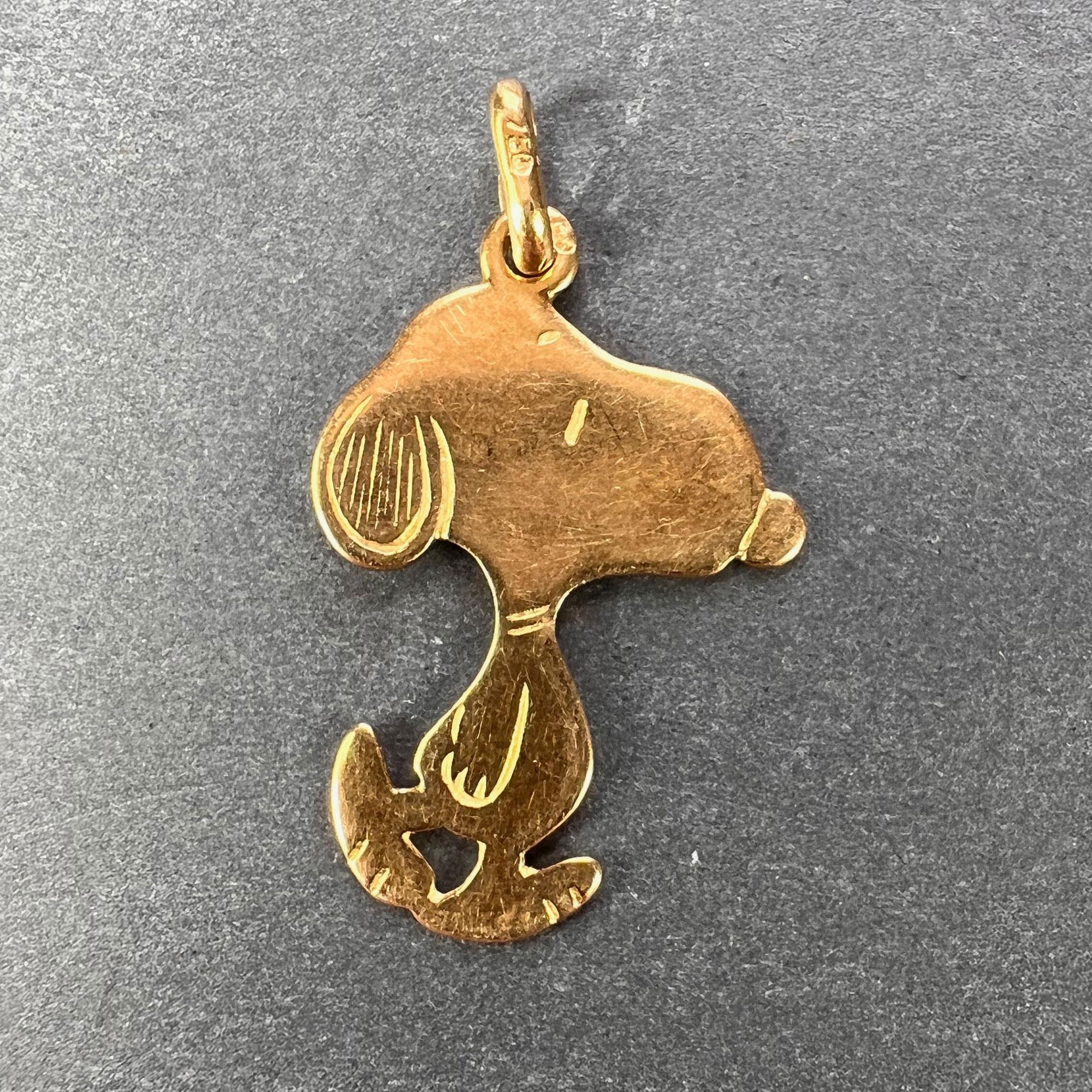 An 18 karat (18K) yellow gold charm pendant designed as the dog Snoopy from the cartoon strip ‘Peanuts’. Stamped with the owl mark for 18 karat gold and French import, and 750 for 18 karat gold to the bail. Also numbered 303 and engraved MOM.
