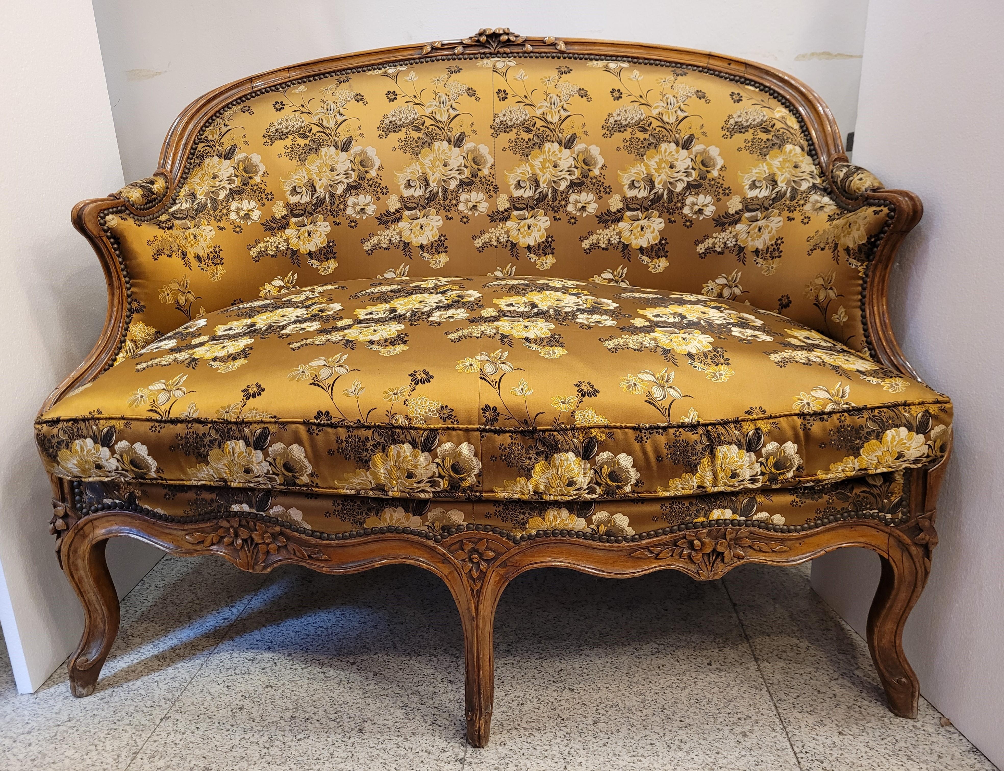 Gorgeous Canapé- sofá en Corbeille, in Louis XV style, made of carved walnut wood with plant decorations and 19th century upholstery in ocher silk with floral print. The Corbeille settee is a type of settee with an oval base, the backrest of which
