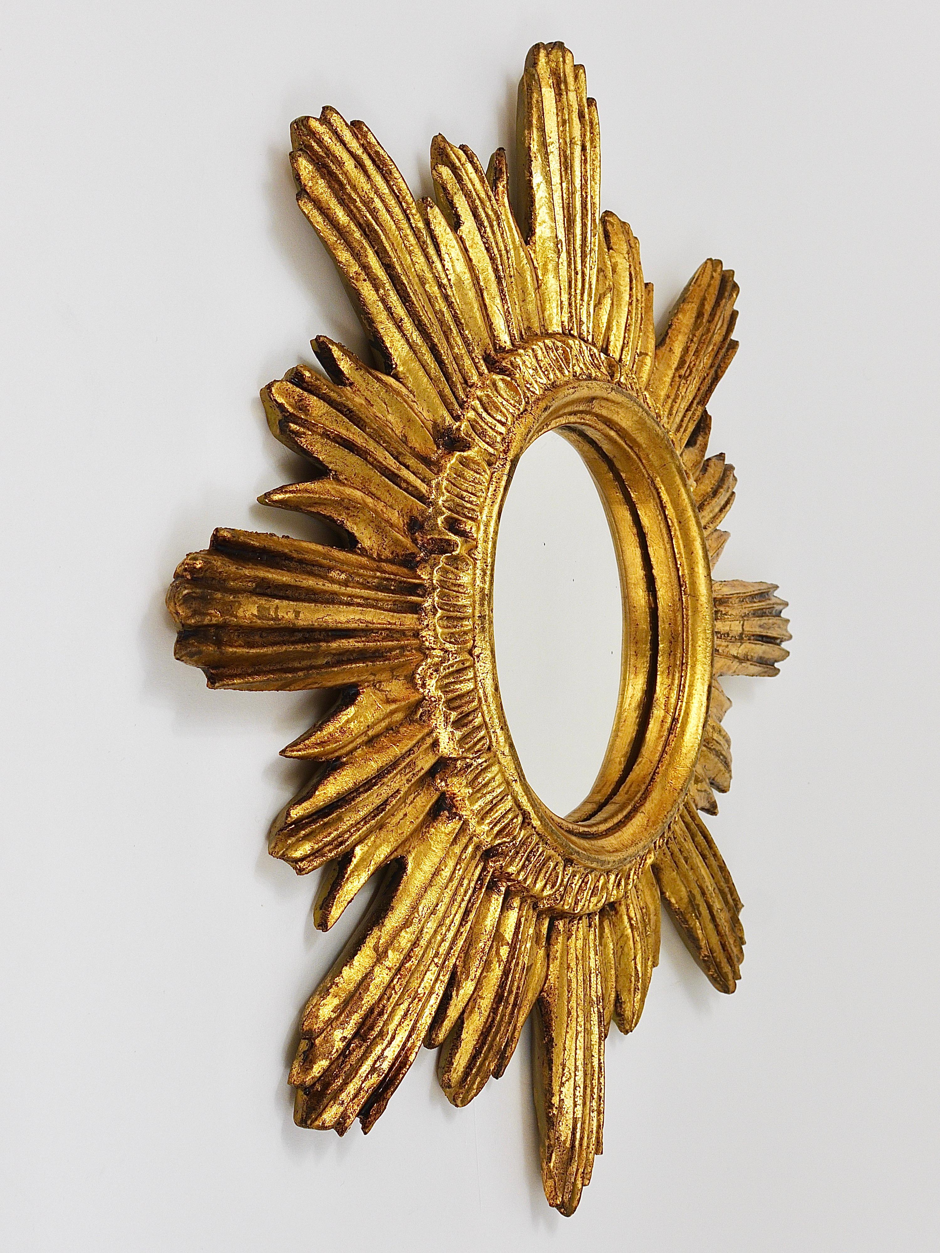 A very beautiful decorative golden mid-century sunburst starburst mirror, made in France in the 1950s. Made of resin still with original mirror glass. Please notice, that there are 3 or 4 very fine and very small black spots in the mirror glass,