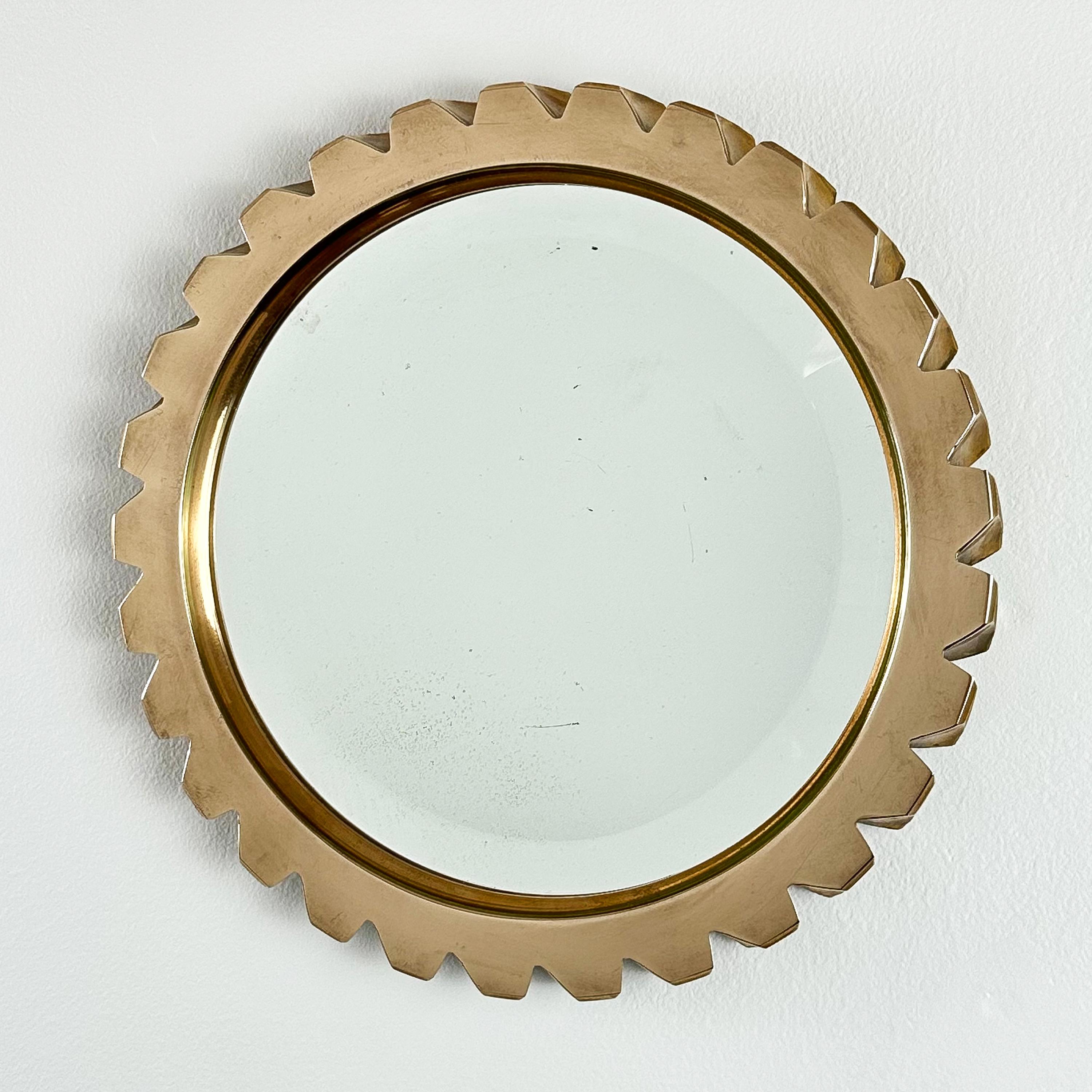 A French solid bronze round wall mirror, circa 1970s. Modern Industrial form resembling a gear.  Polished solid bronze surrounds a 8.25” diameter beveled mirror. Bevel is 5/8”.  Bronze is in excellent condition.  Minor age spots to the mirror. 