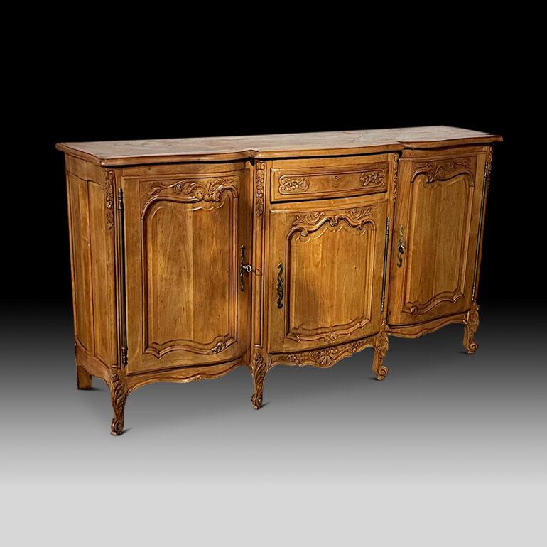 A French Louis XV serpentine-front buffet with three shaped-paneled doors with carved details and a single upper centre drawer. Solid cherry throughout and with a lovely warm patina.
     