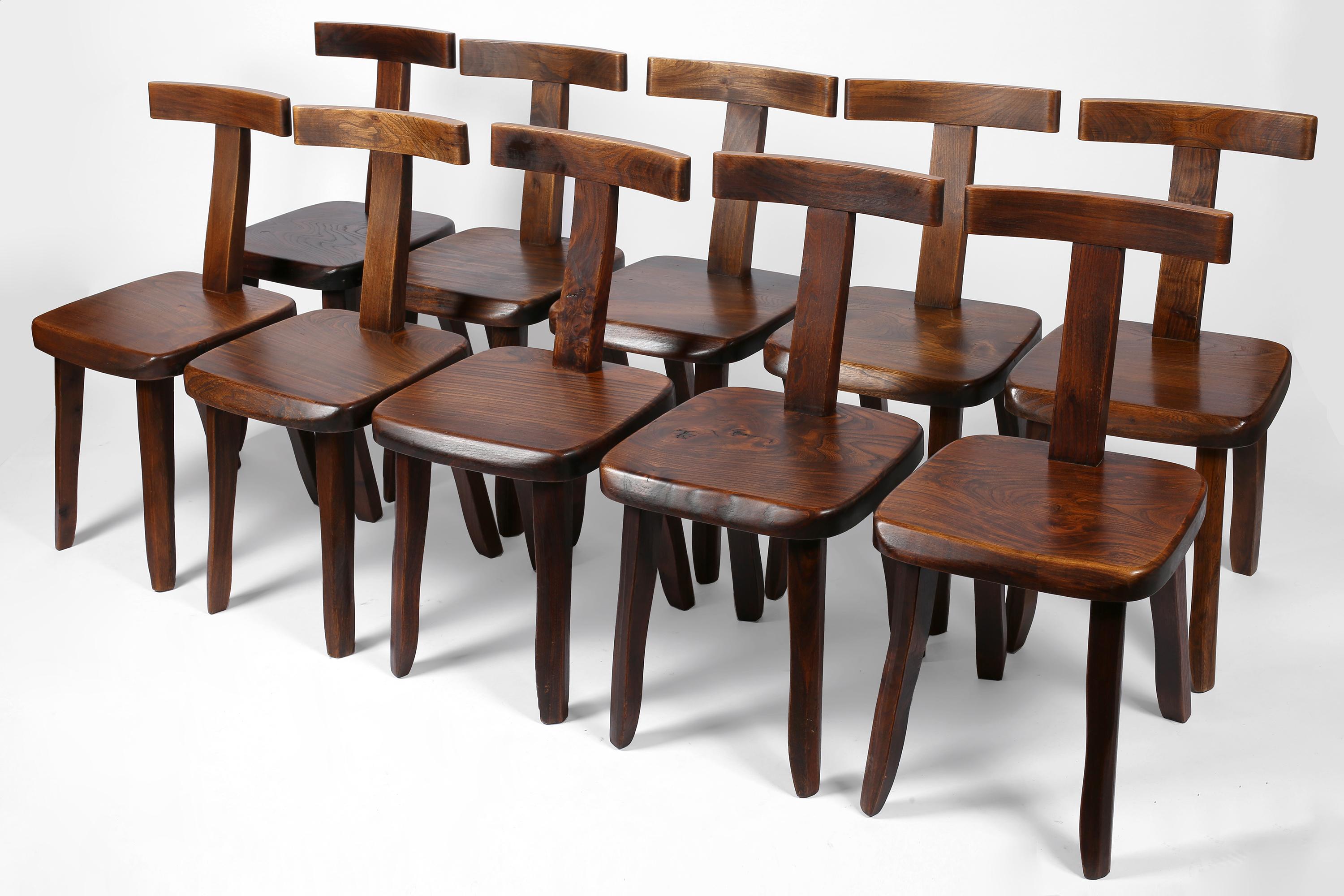 A run of ten dining or side chairs in carved and dark stained solid elm with ‘T’ shaped backrests and organic, freeform legs. A model commonly attributed to Finnish designer Olavi Hanninen. French, c. 1950s.