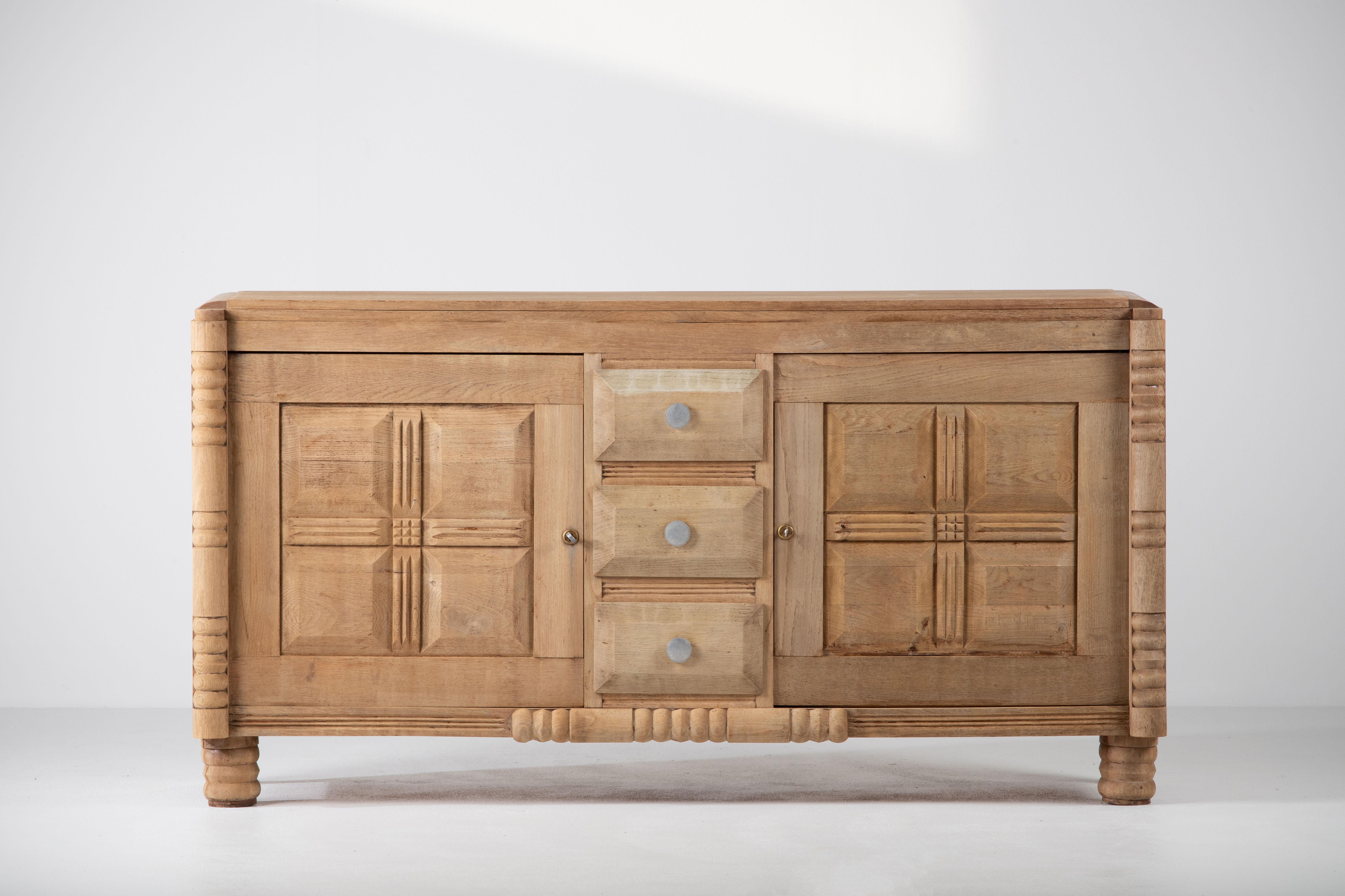 Very elegant Credenza in solid oak, France, 1940s.
Art Deco Brutalist sideboard. 
The credenza consists of Two storage facilities covered with graphic designed doors and a column of drawers.
The refined wooden structures on the doors create a