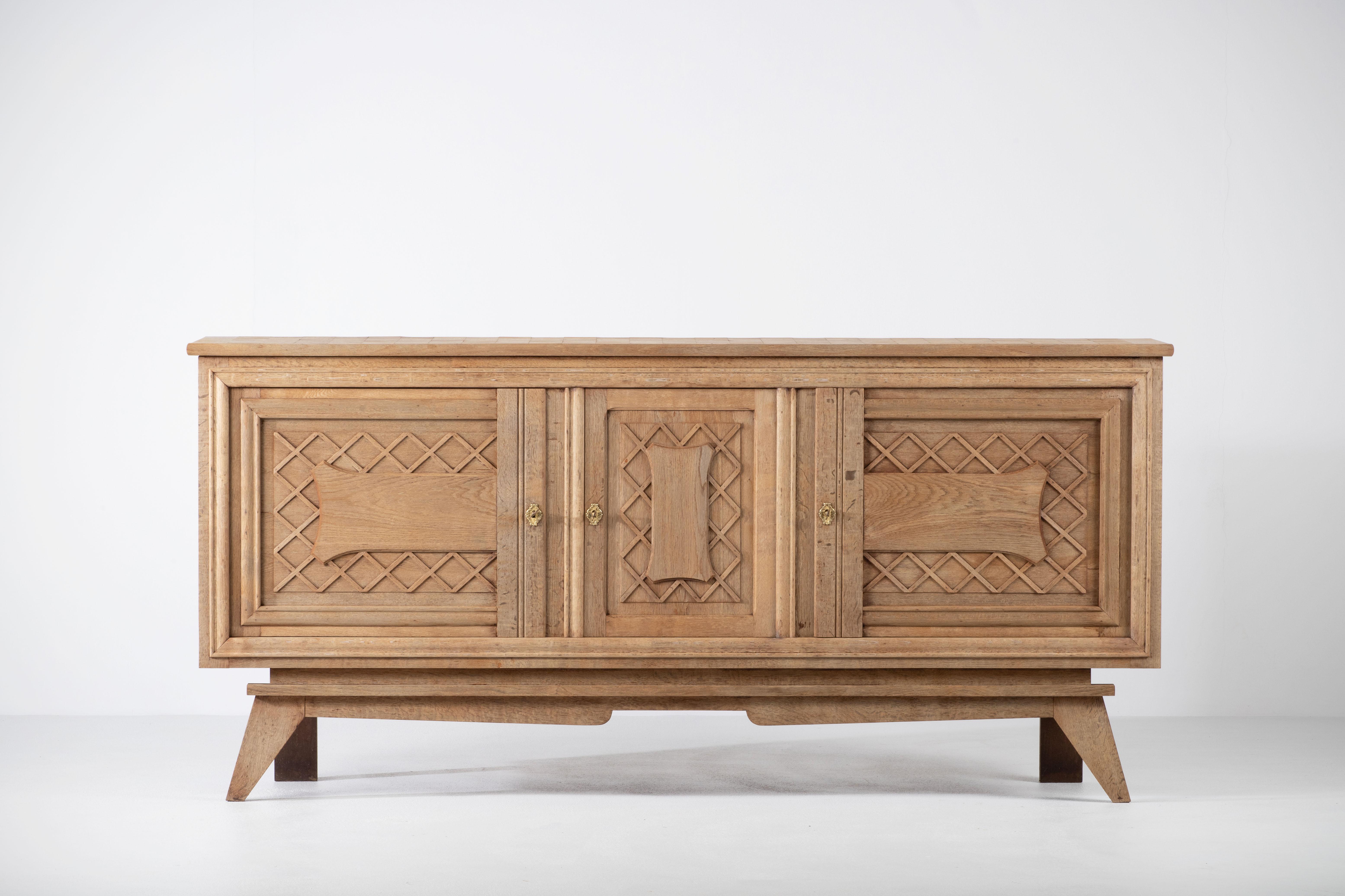 Very elegant Credenza in solid oak, France, 1940s.
Art Deco Brutalist sideboard. 
The credenza consists of Two storage facilities covered with graphic designed doors and a column of drawers.
The refined wooden structures on the doors create a