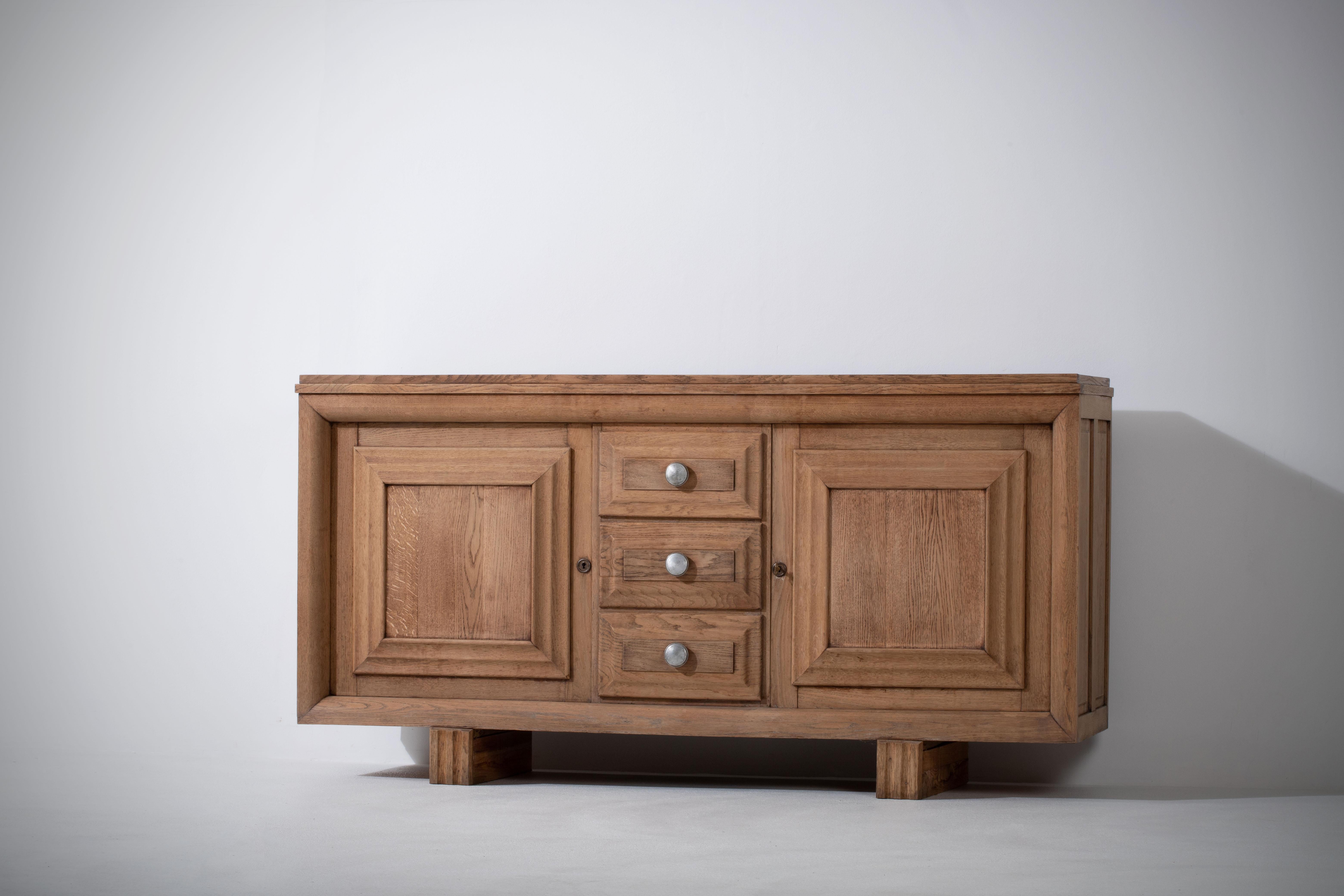 Very elegant credenza in solid oak, France, 1940s.
Art Deco brutalist sideboard. 
The credenza consists of two storage facilities covered and a column of drawers.
The refined wooden structures on the doors create a striking combination with the