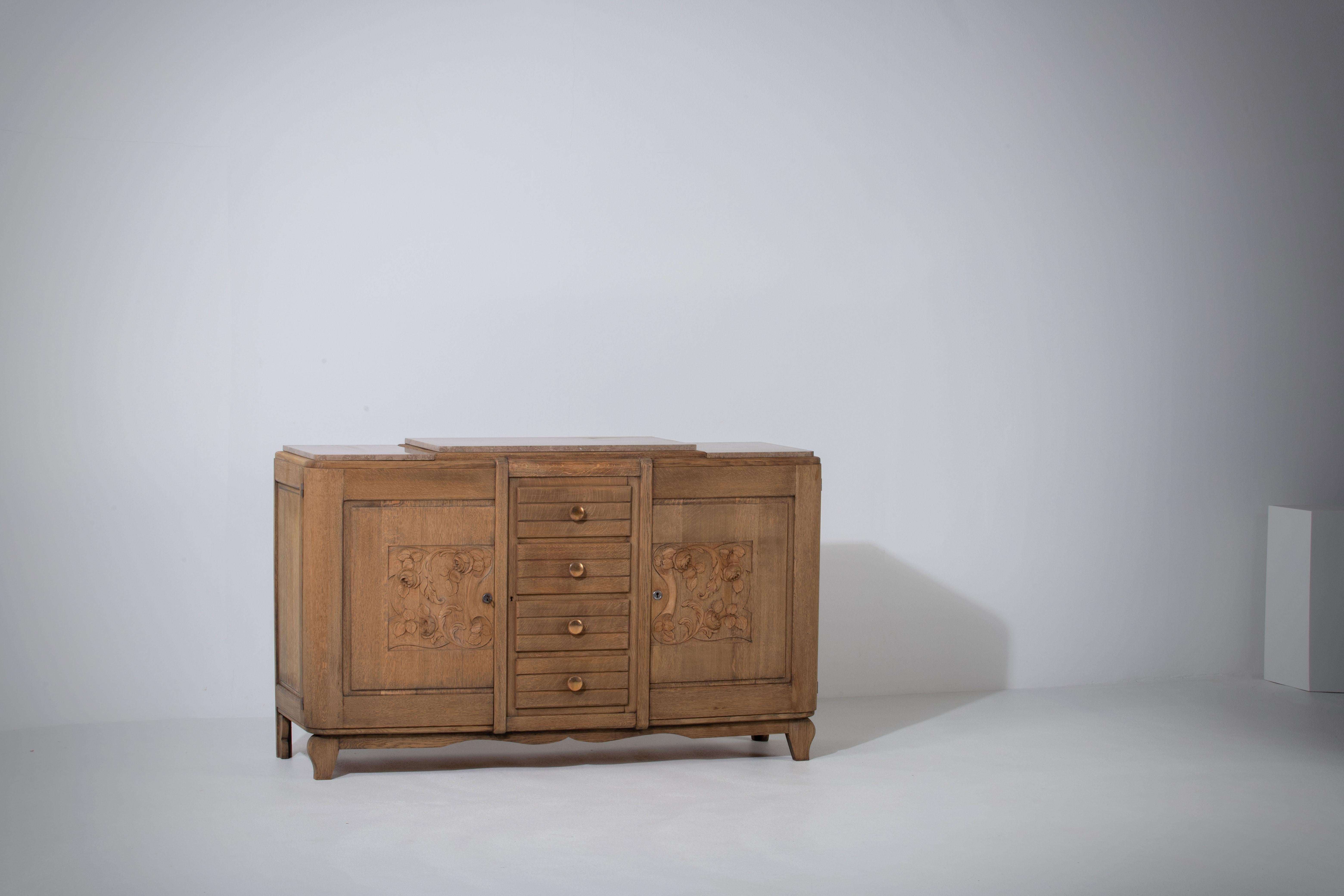 Very elegant credenza in solid oak, France, 1940s.
Art Deco Brutalist sideboard. 
The credenza consists of two storage facilities covered with hand carved designed doors and in the center a drawers column.
The refined wooden structures on the