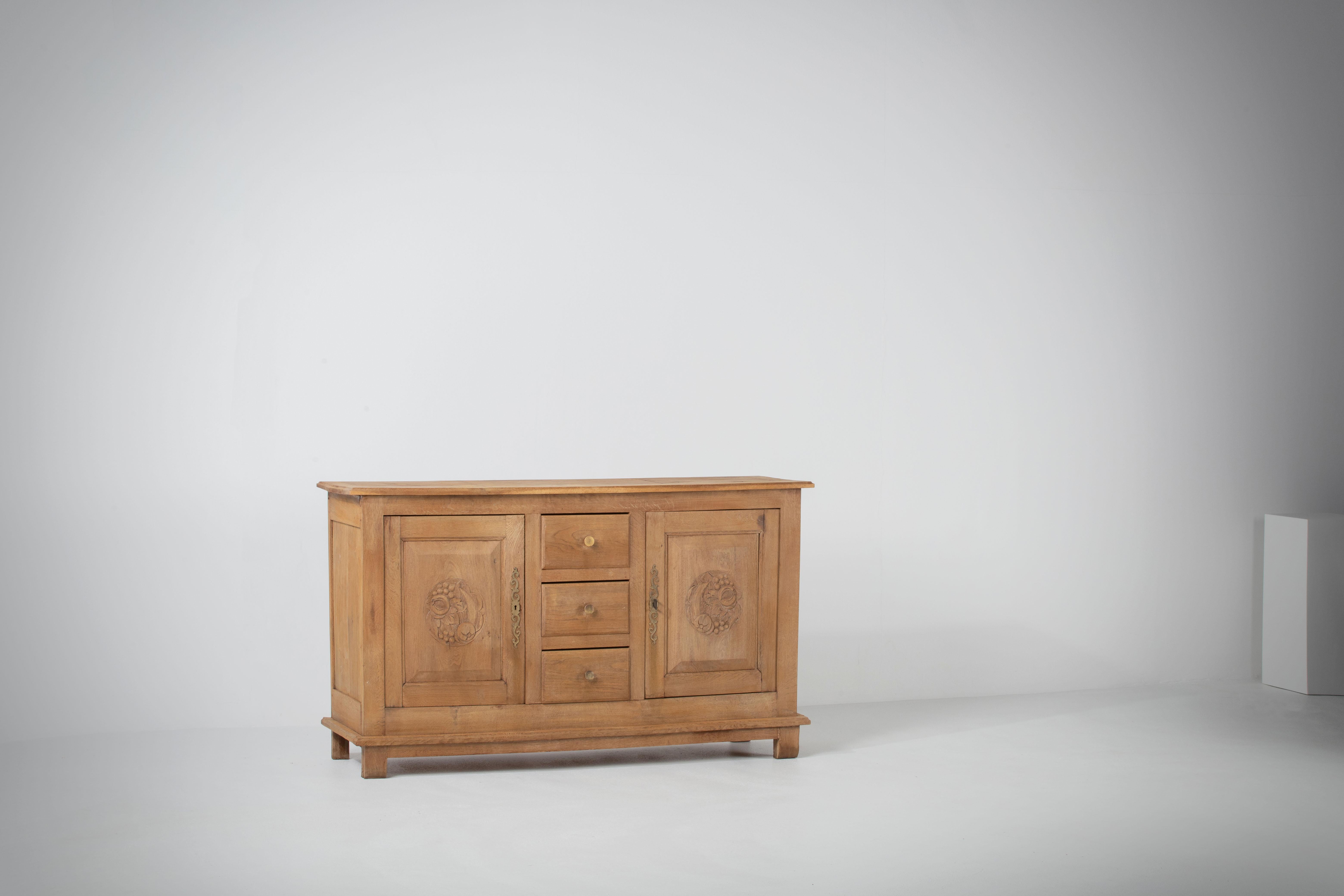 Very elegant credenza in solid oak, France, 1940s.
Art Deco Brutalist sideboard. 
The credenza consists of Two storage facilities covered with hand-carved designed doors and a column of drawers.
The refined wooden structures on the doors create a