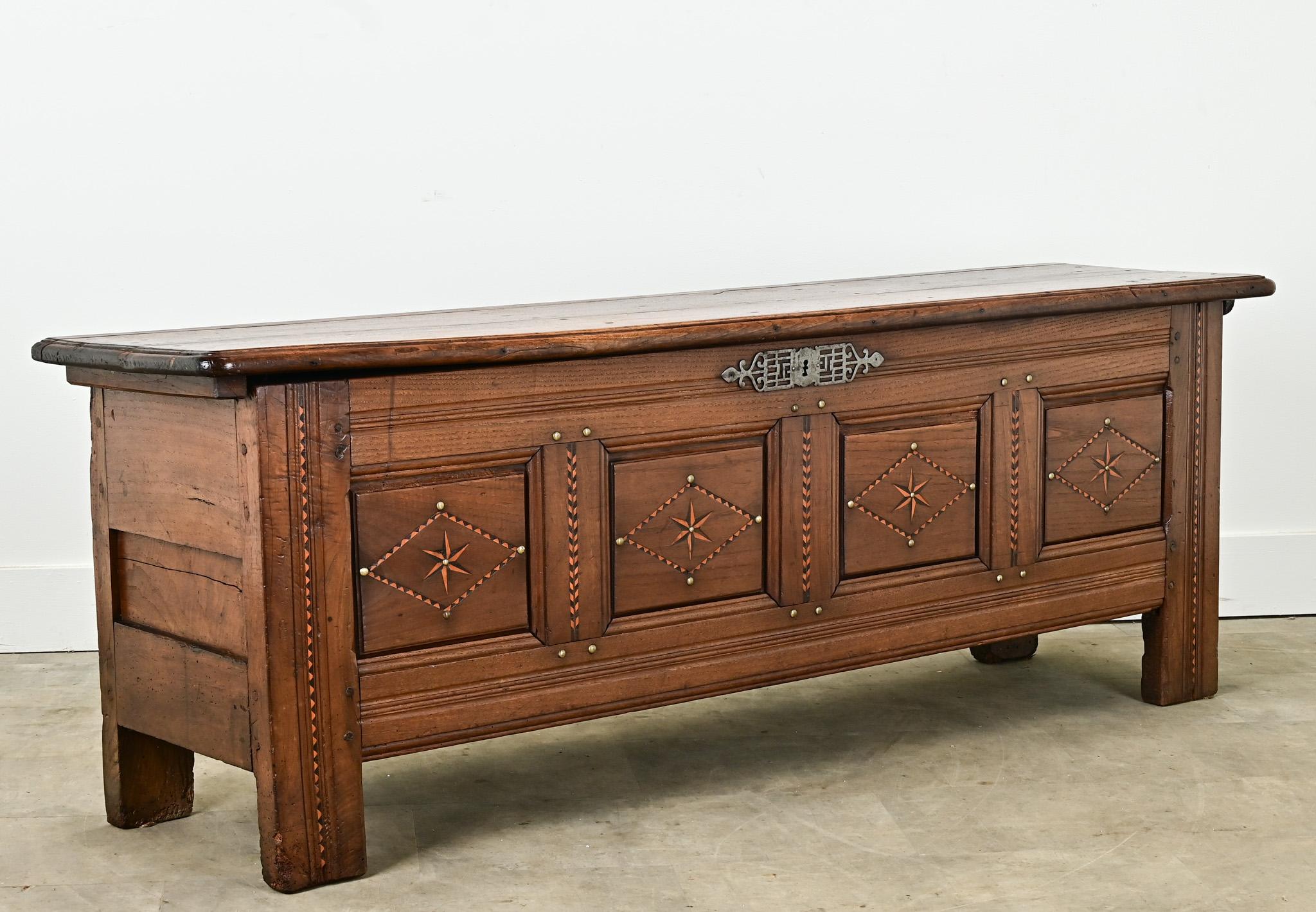 A long and narrow French solid oak and inlay paneled coffer. The facade has geometric inlay designs of alternating ebonized wood and satinwood with hand forged nailheads. The top, made of two solid boards, opens on hand forged iron hinges to an open