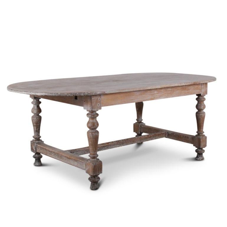 A French, solid planked oak trestle table with a bleached and worn painted finish. Circa 1920.



    
